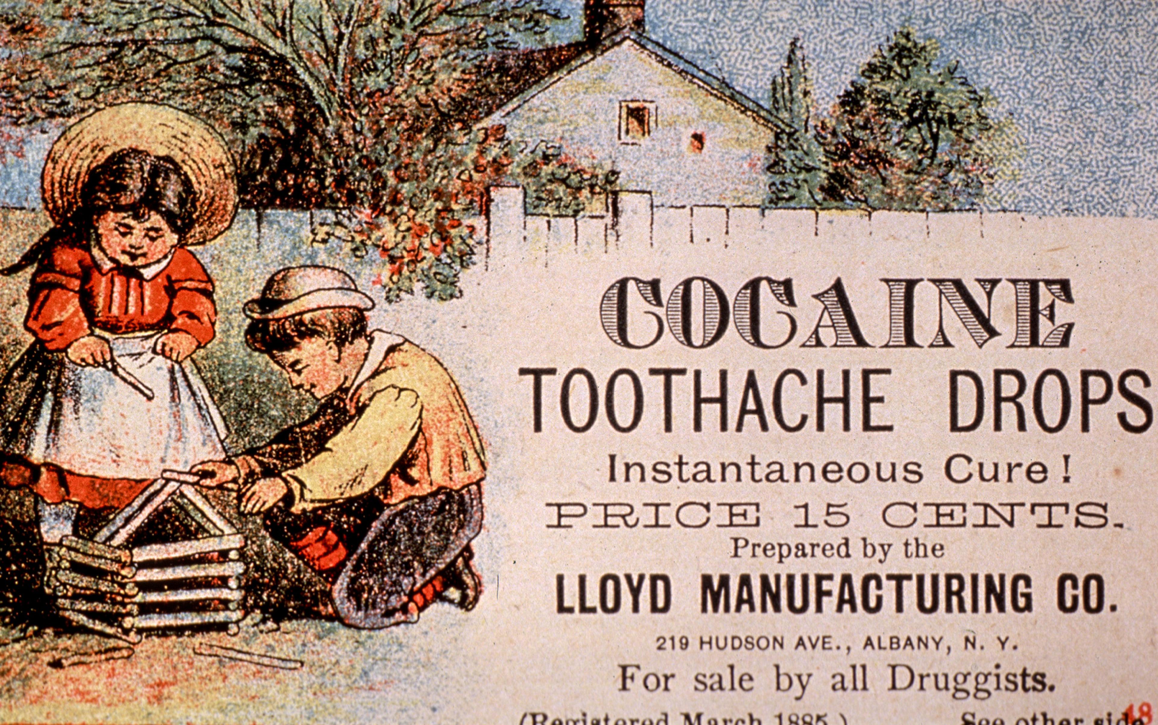 Vintage advertising poster for ‘Cocaine Toothache Drops’ featuring two children playing happily, building a house from sticks, in front of a house with a wooden fence.