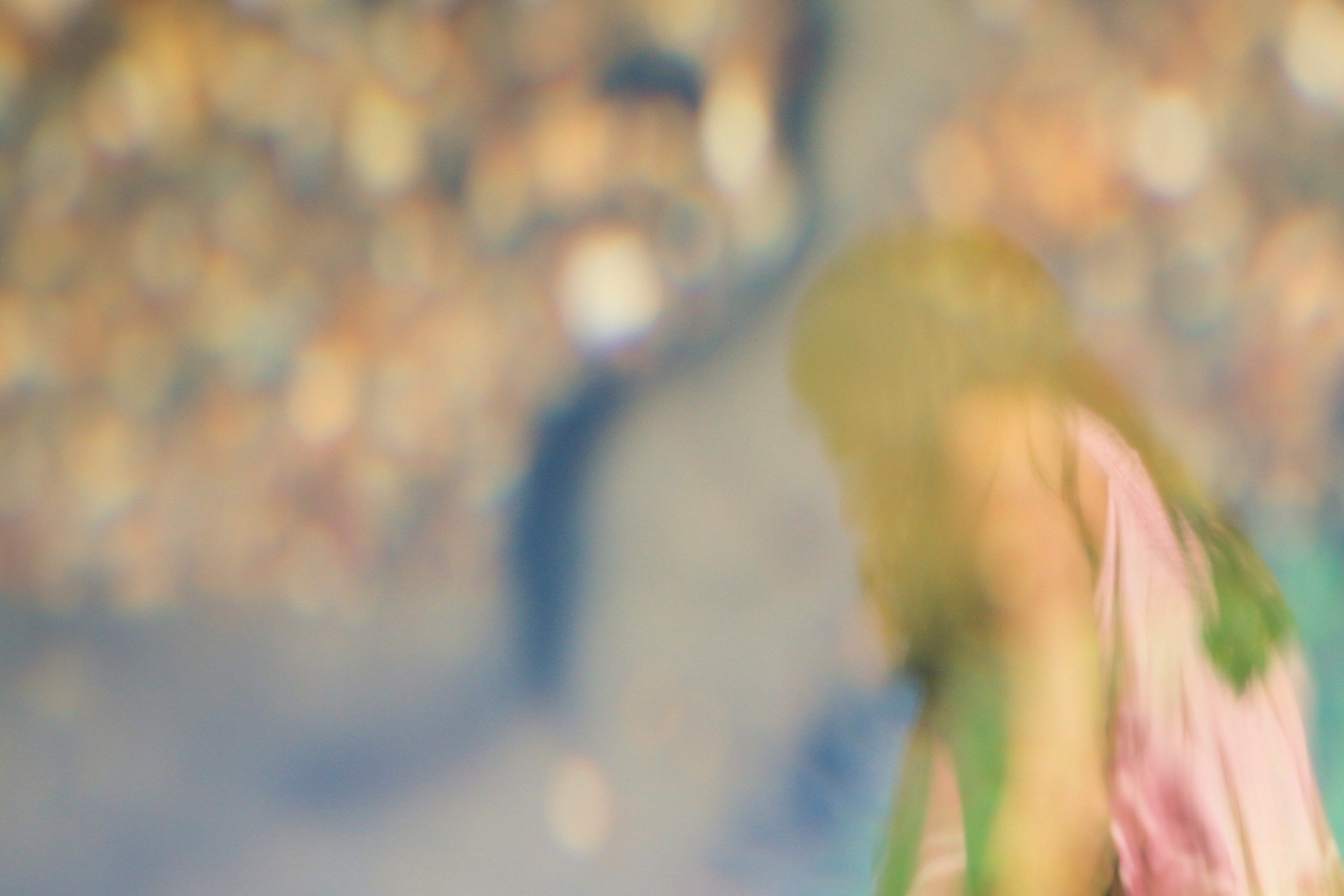 Blurry photo of a person in a pink top with a colourful bokeh background.