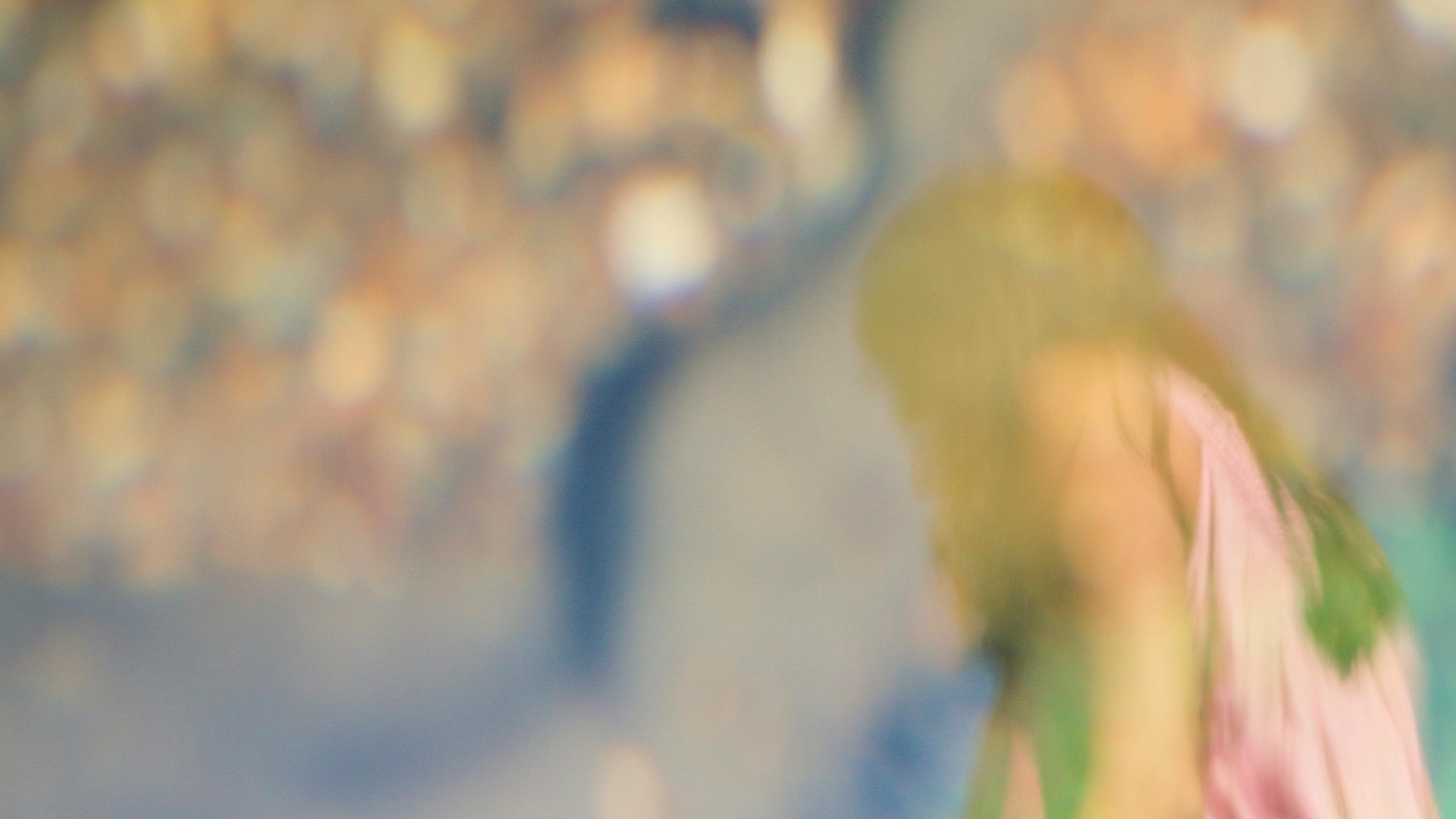 Blurry photo of a person in a pink top with a colourful bokeh background.