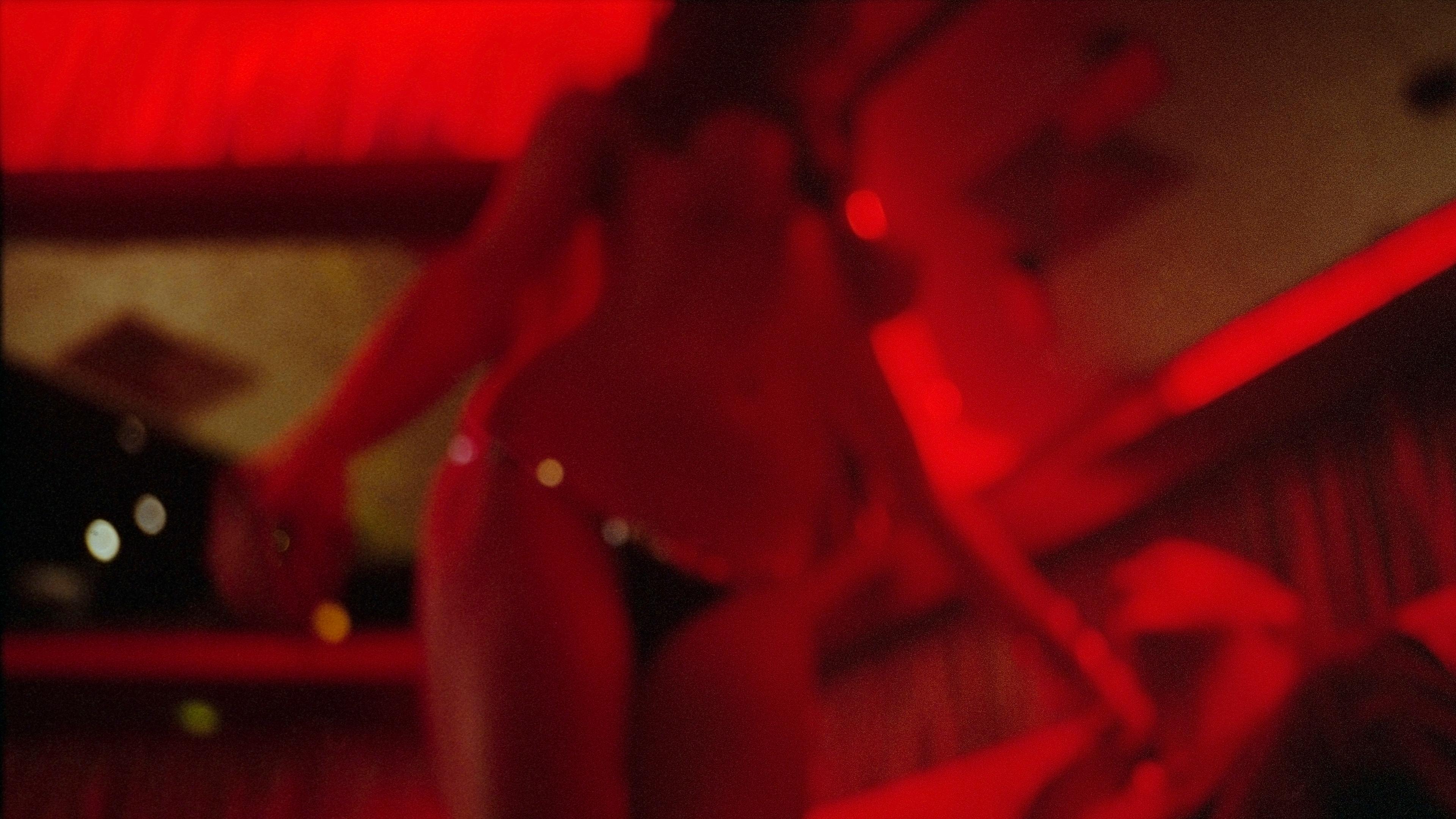 Blurry photo of a dimly lit interior with a person in swimwear under red lighting.