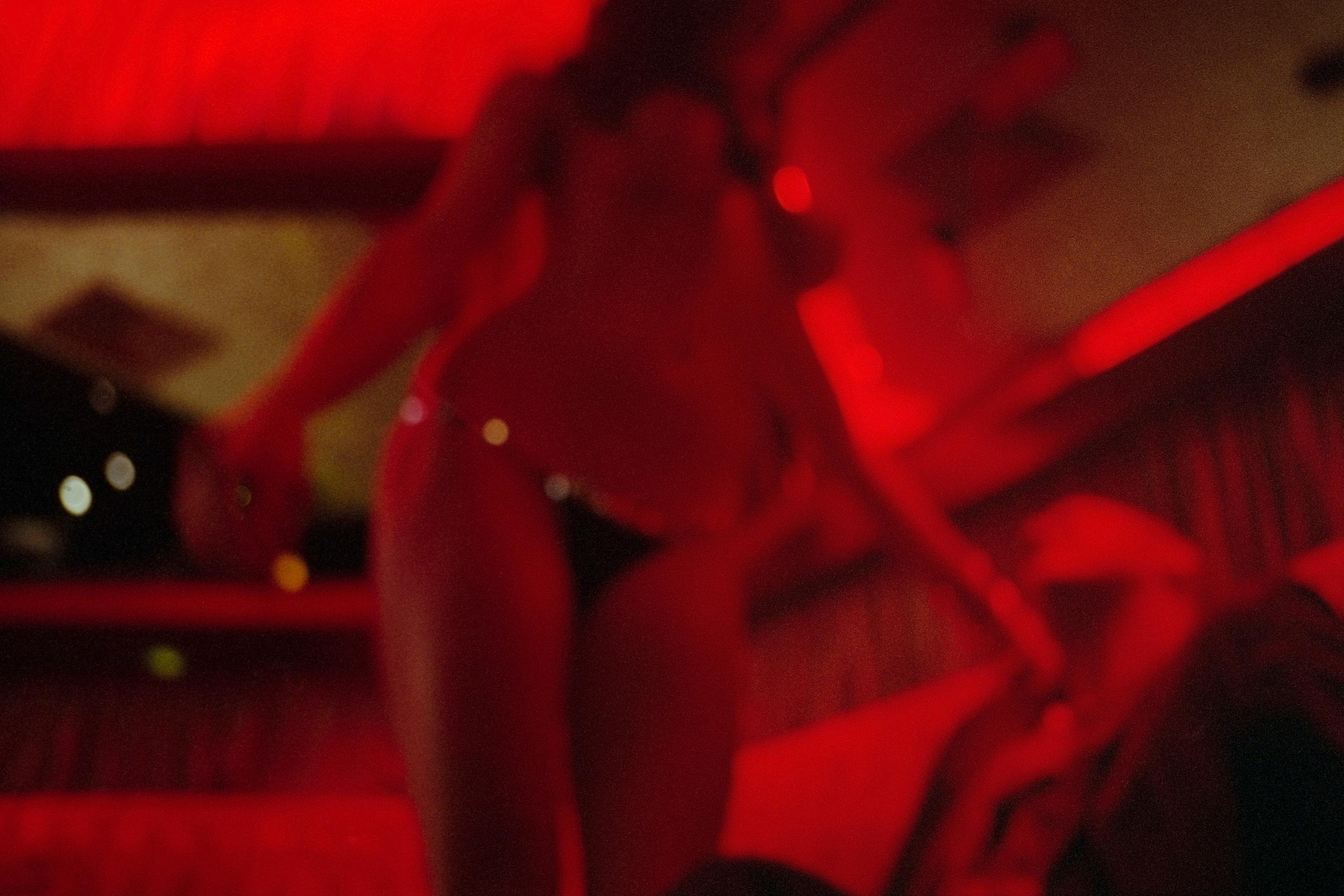 Blurry photo of a dimly lit interior with a person in swimwear under red lighting.