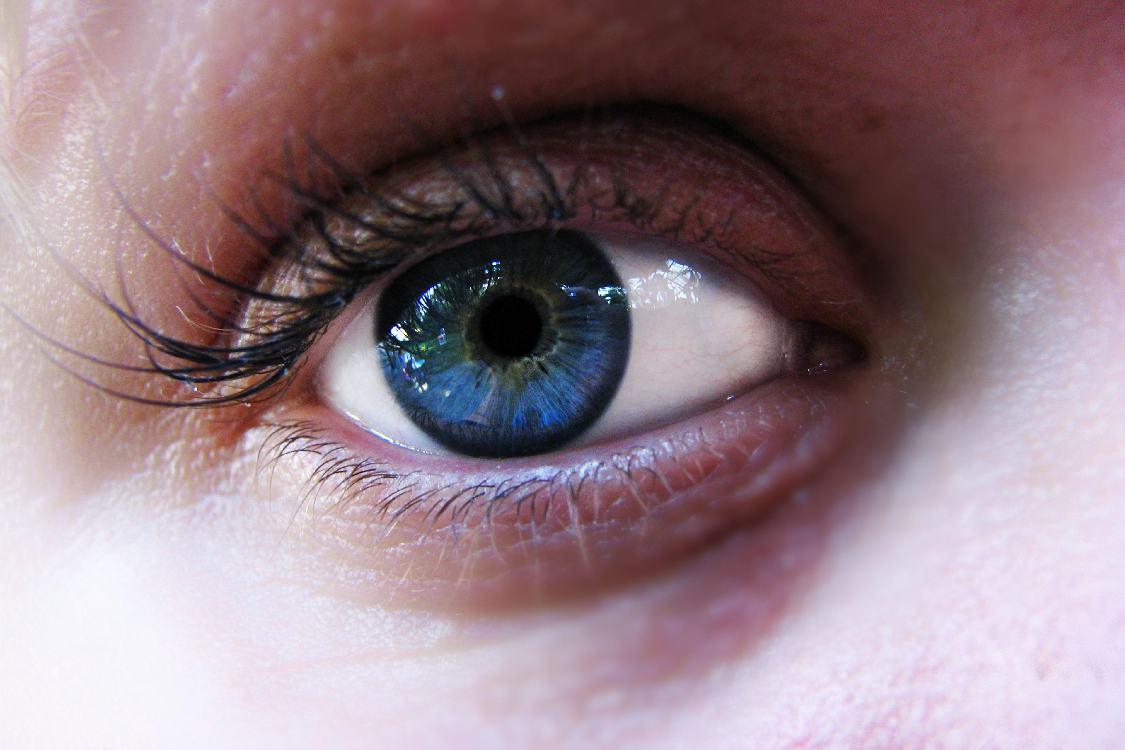 Close-up photo of a blue eye with detailed lashes and skin texture visible.