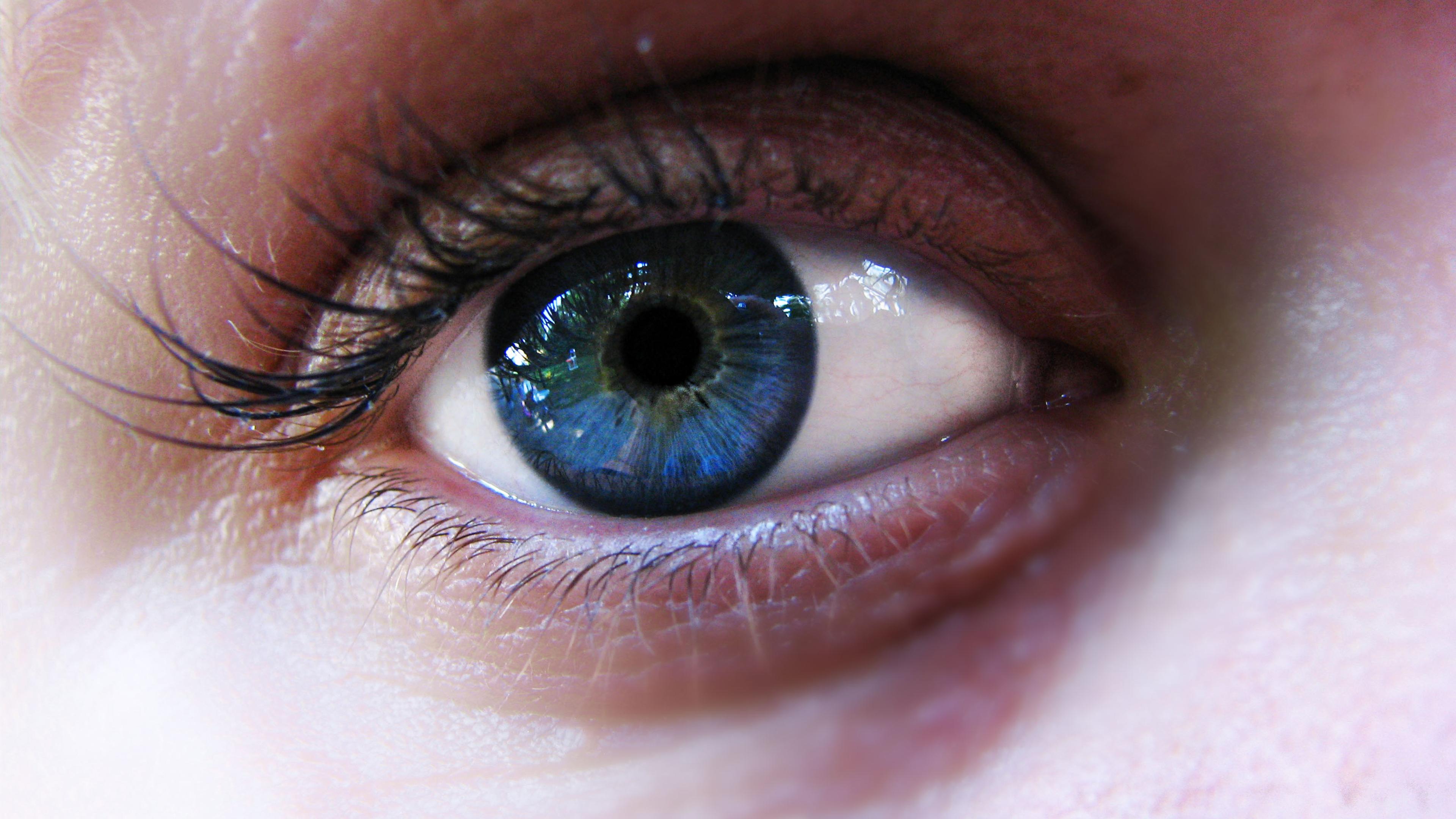 Close-up photo of a blue eye with detailed lashes and skin texture visible.