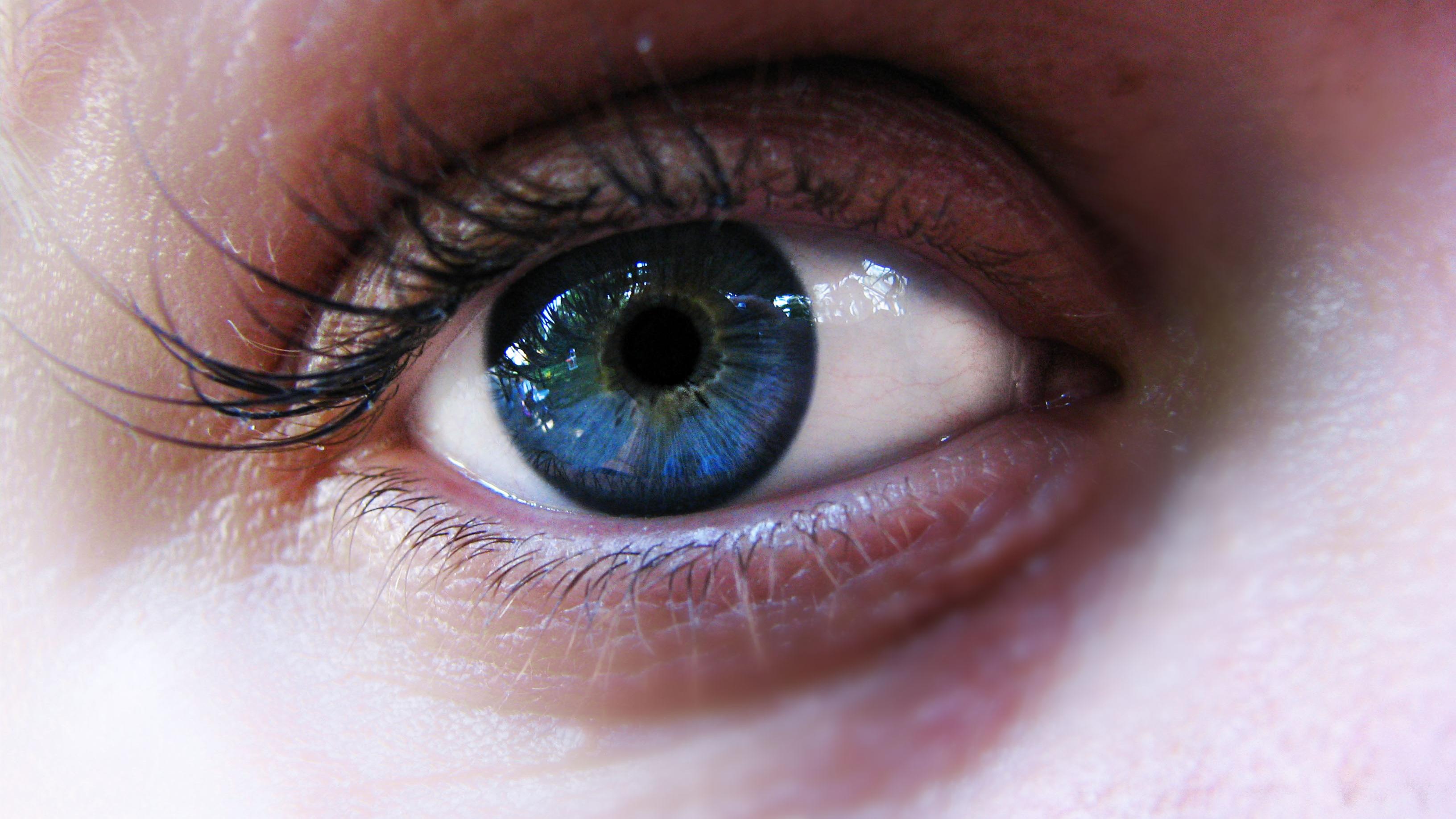 Close-up photo of a blue eye with detailed lashes and skin texture visible.