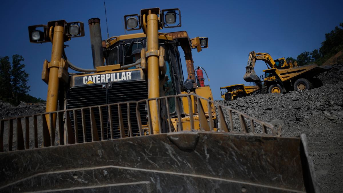 A bulldozer and excavator at a quarry with a clear blue sky in the background.