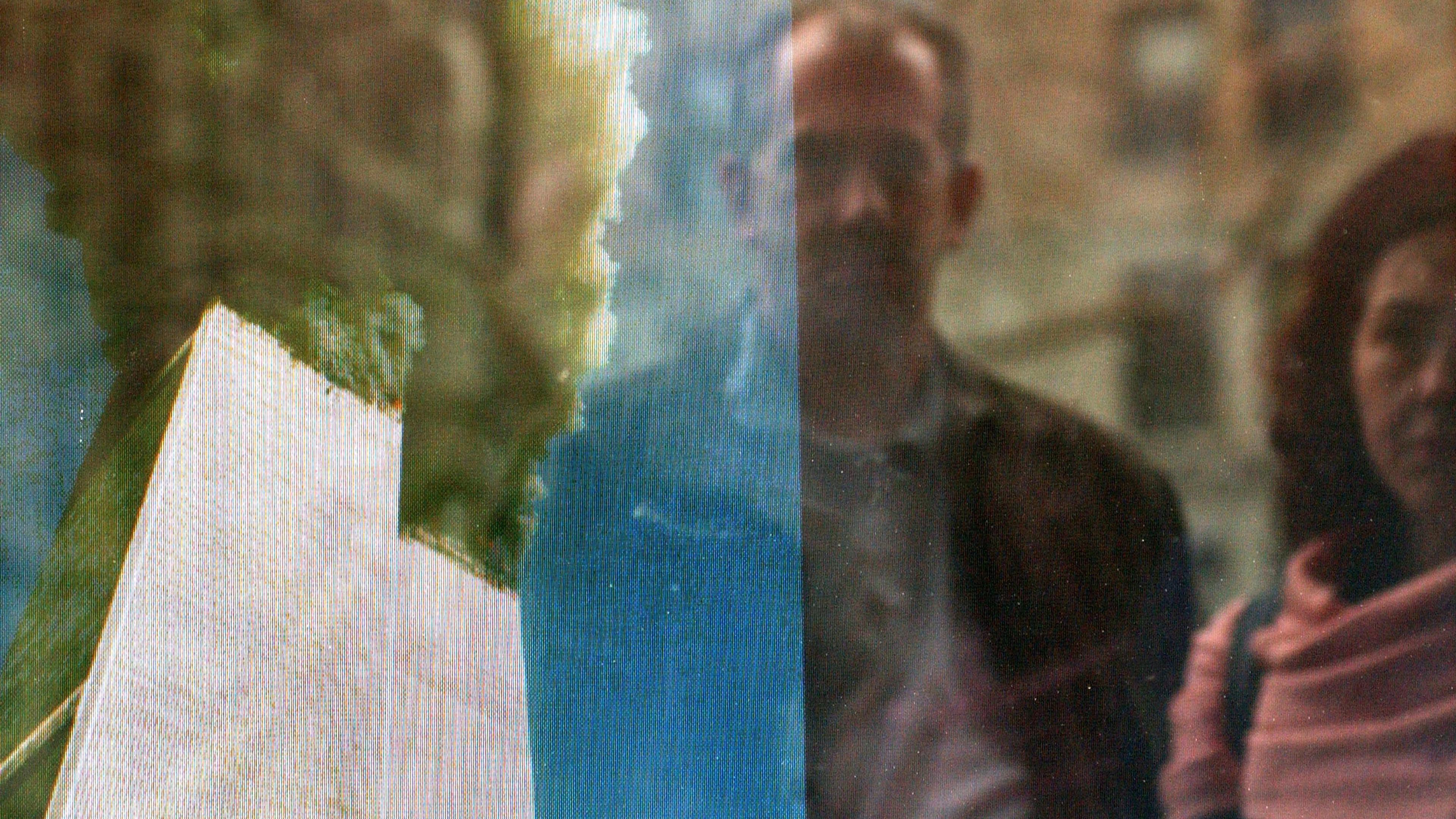 Photo of a burning tower with smoke, reflects a man and woman standing nearby in an urban setting.