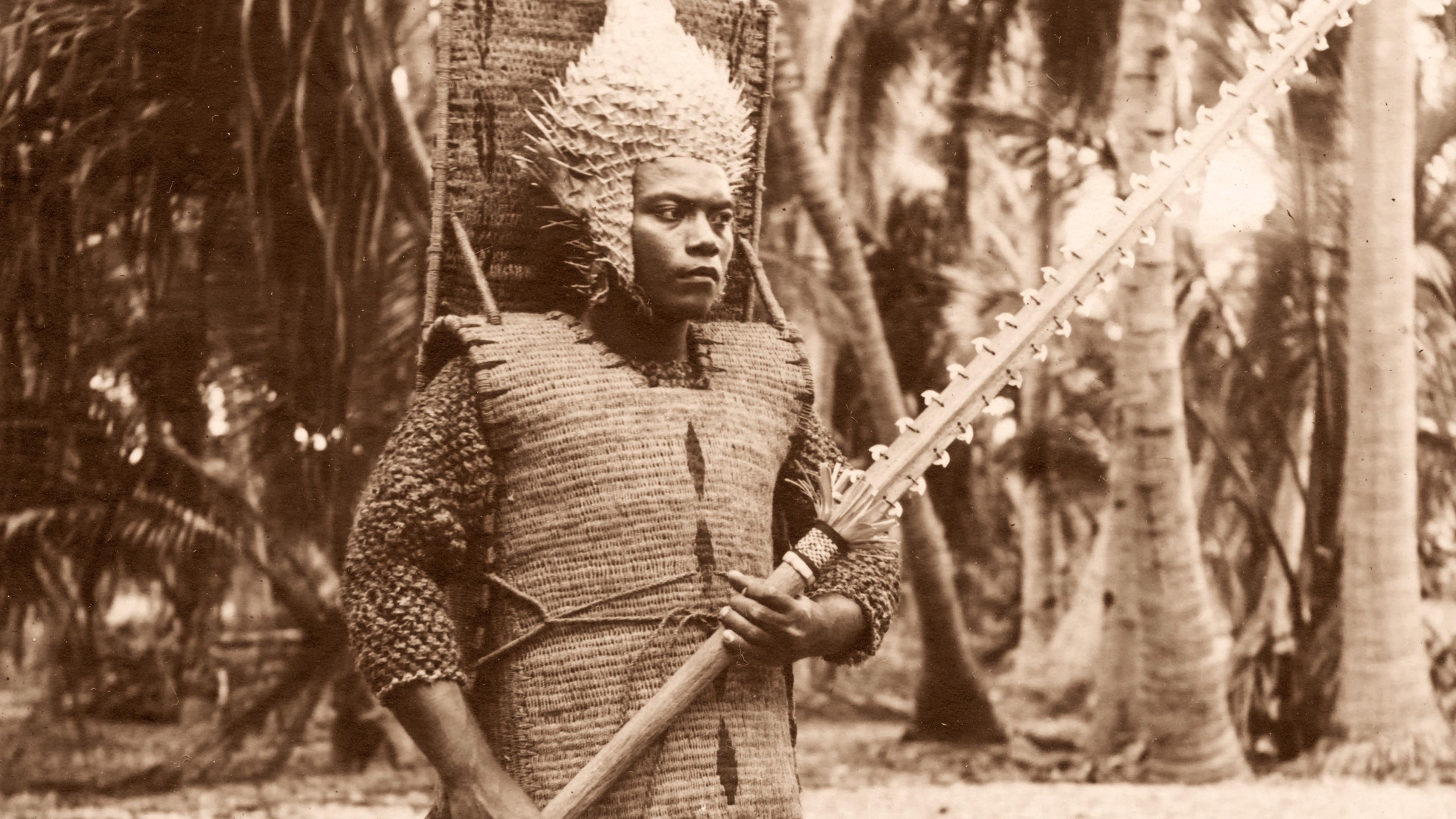 Sepia-toned photo of a person in traditional armour with a spiked helmet holding a weapon in a forest setting.