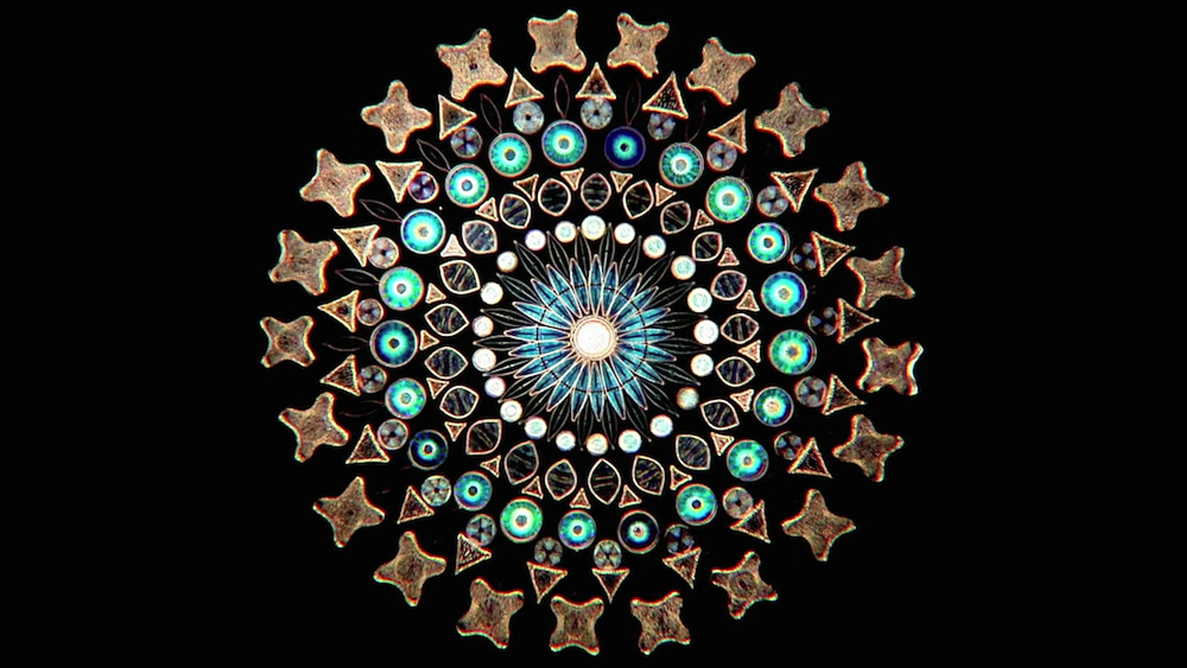 A circular, colourful mandala-like pattern made from various geometric shapes and stars, against a black background.