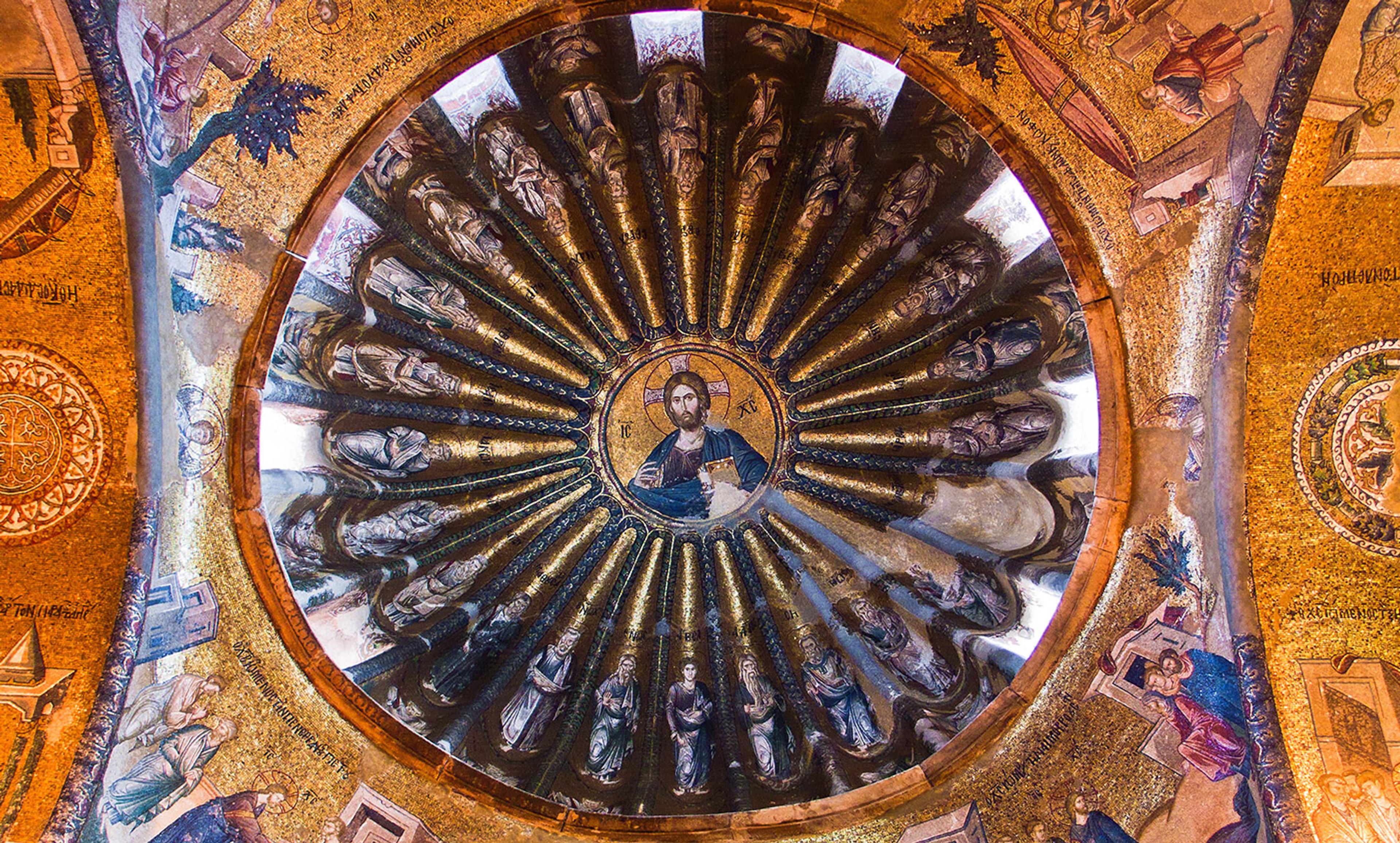 A circular mosaic painting on a domed ceiling depicting a central religious figure surrounded by smaller figures with gold accents.