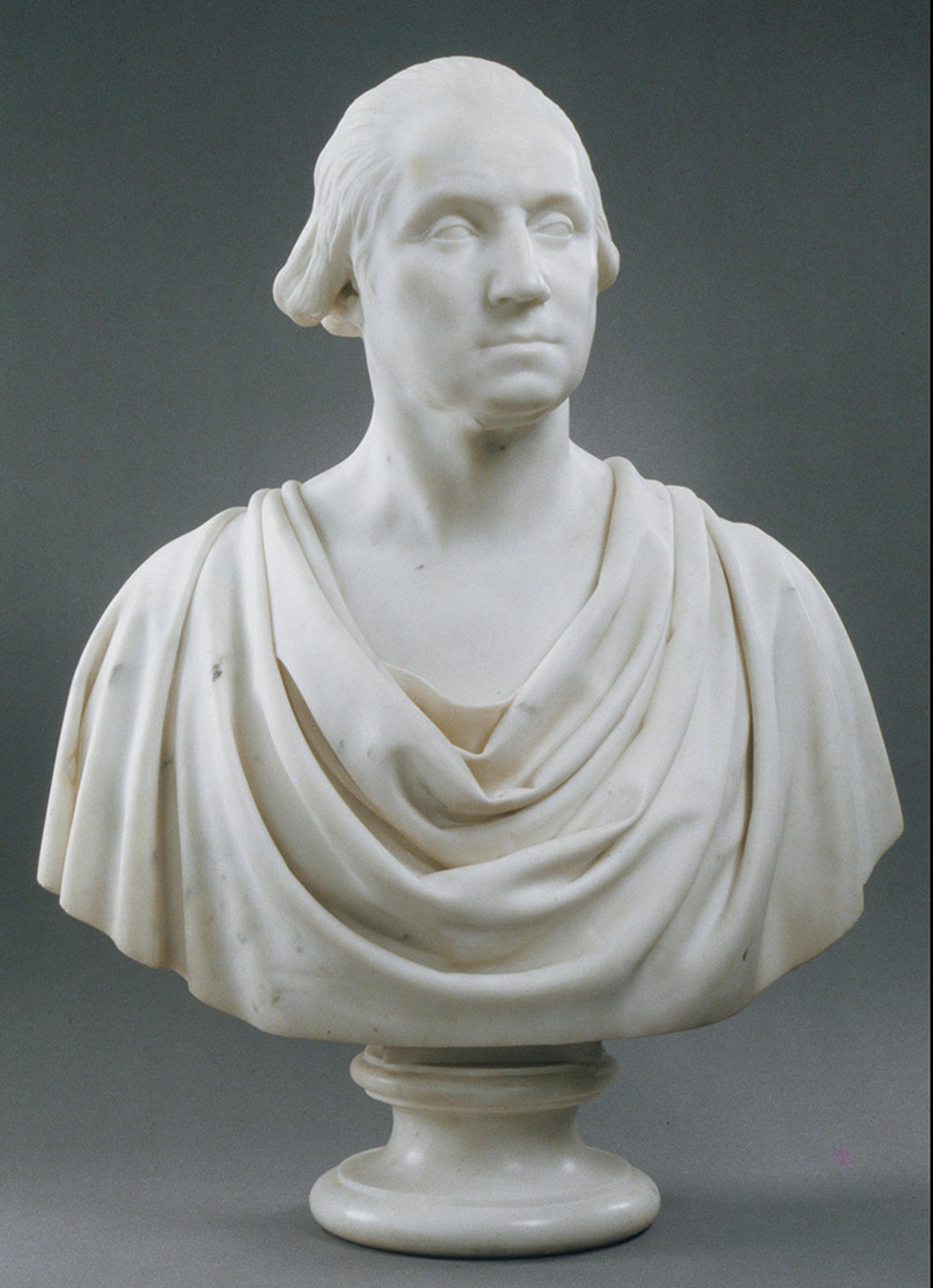 Marble bust of a man with a draped garment against a dark background, showcasing detailed sculpting.