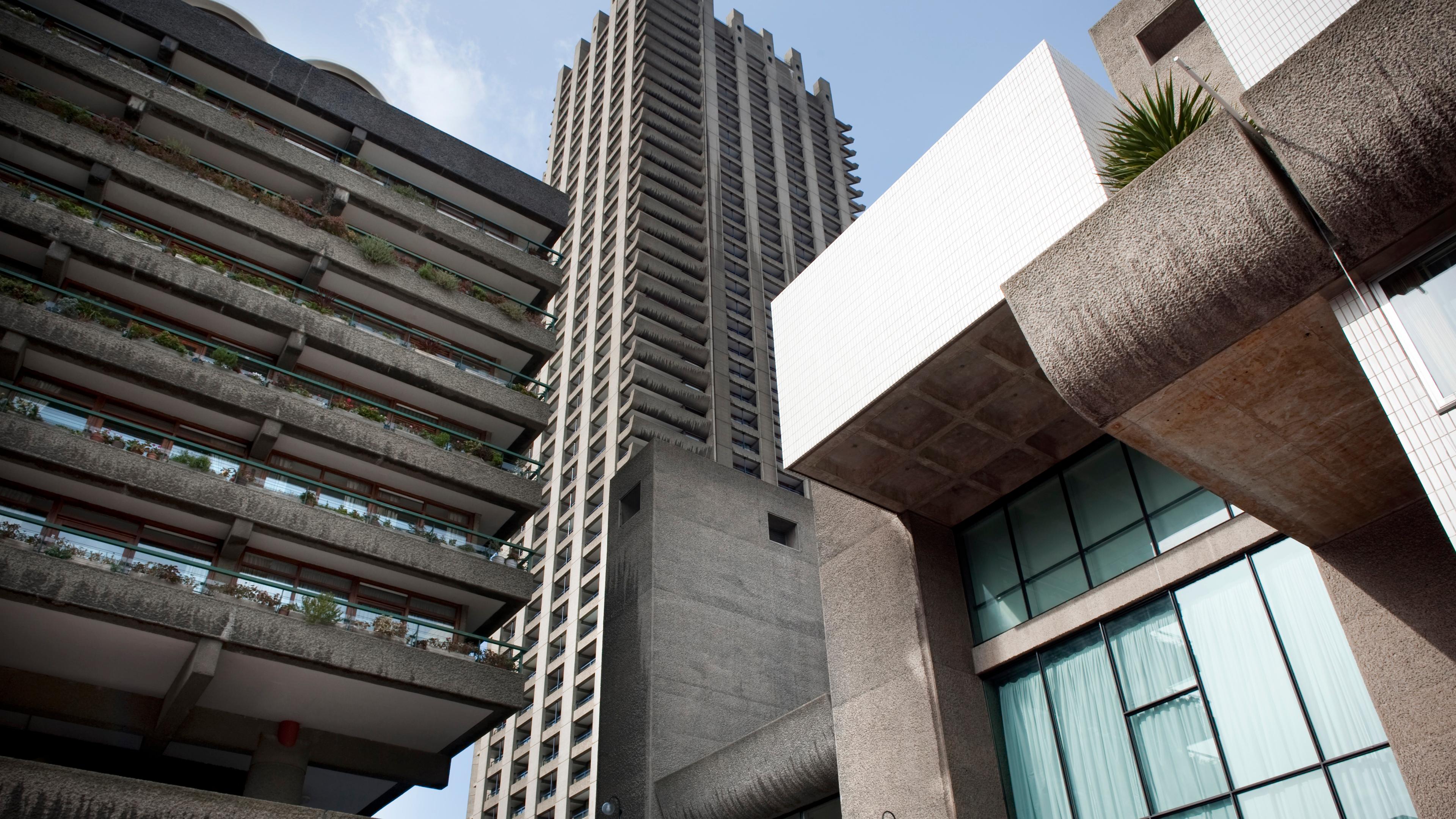 Photo of Brutalist architecture showing concrete buildings and a high-rise tower against a clear blue sky.