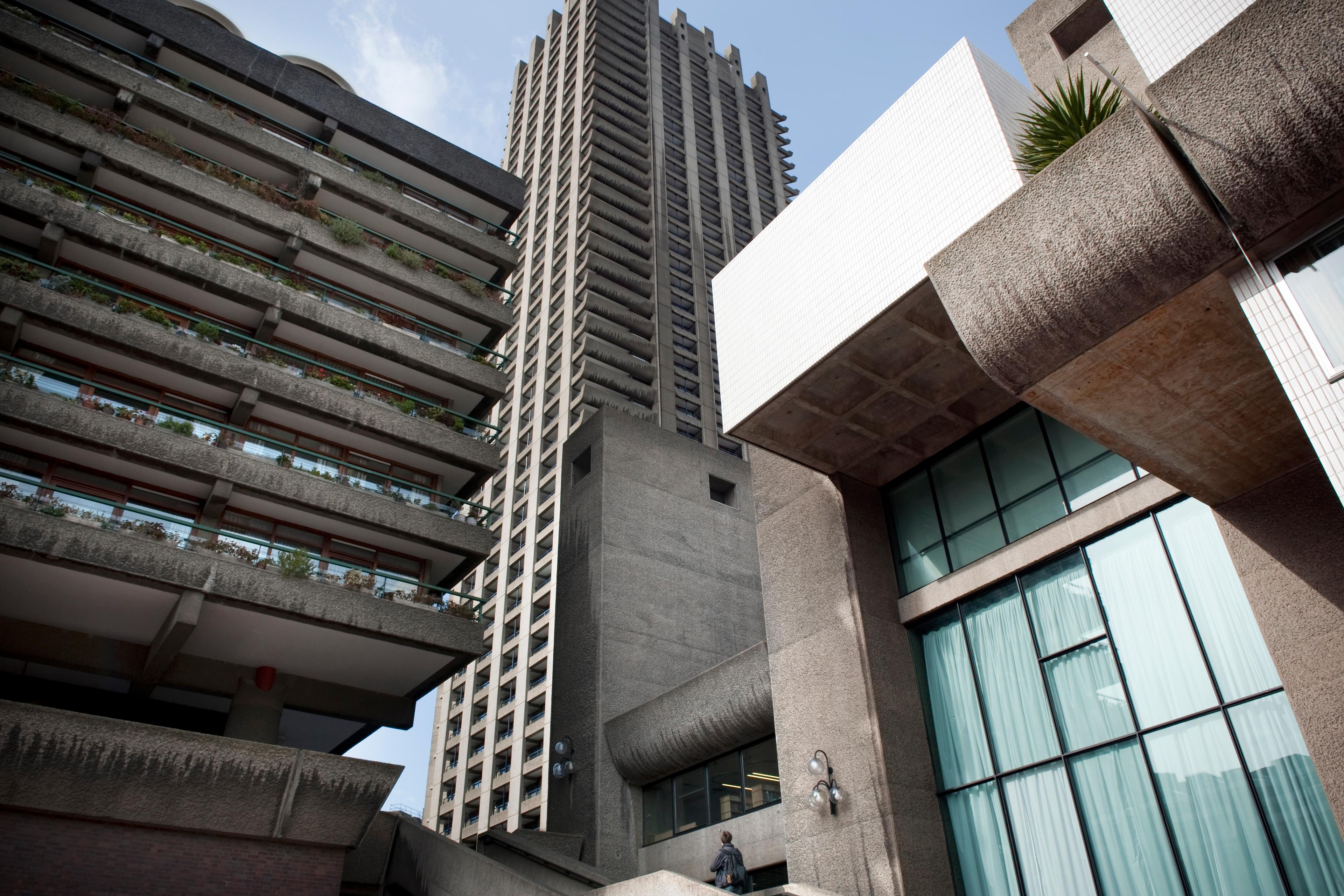 Photo of Brutalist architecture showing concrete buildings and a high-rise tower against a clear blue sky.