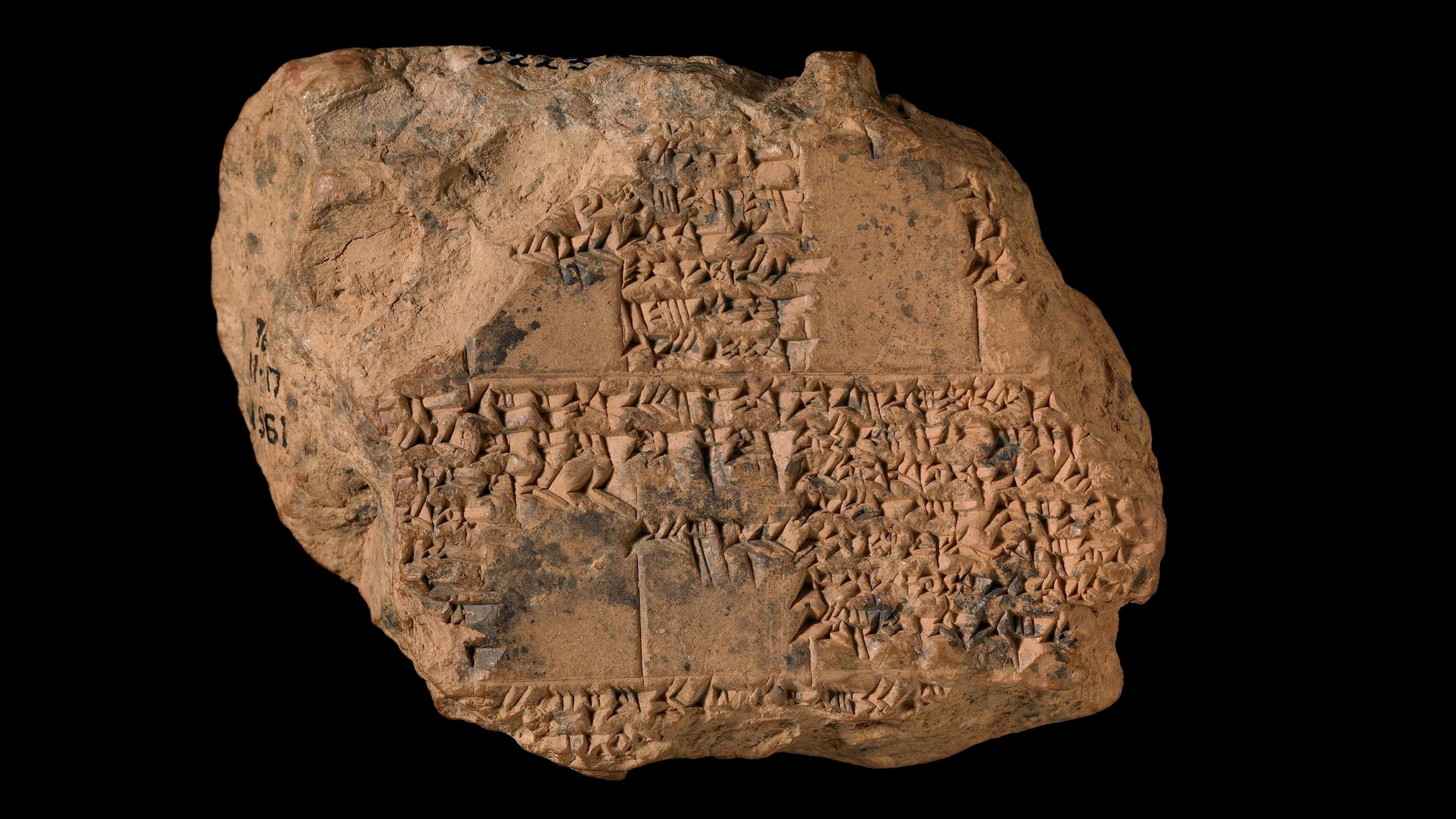 Ancient clay tablet with cuneiform script on a black background, likely an artifact from Mesopotamia.