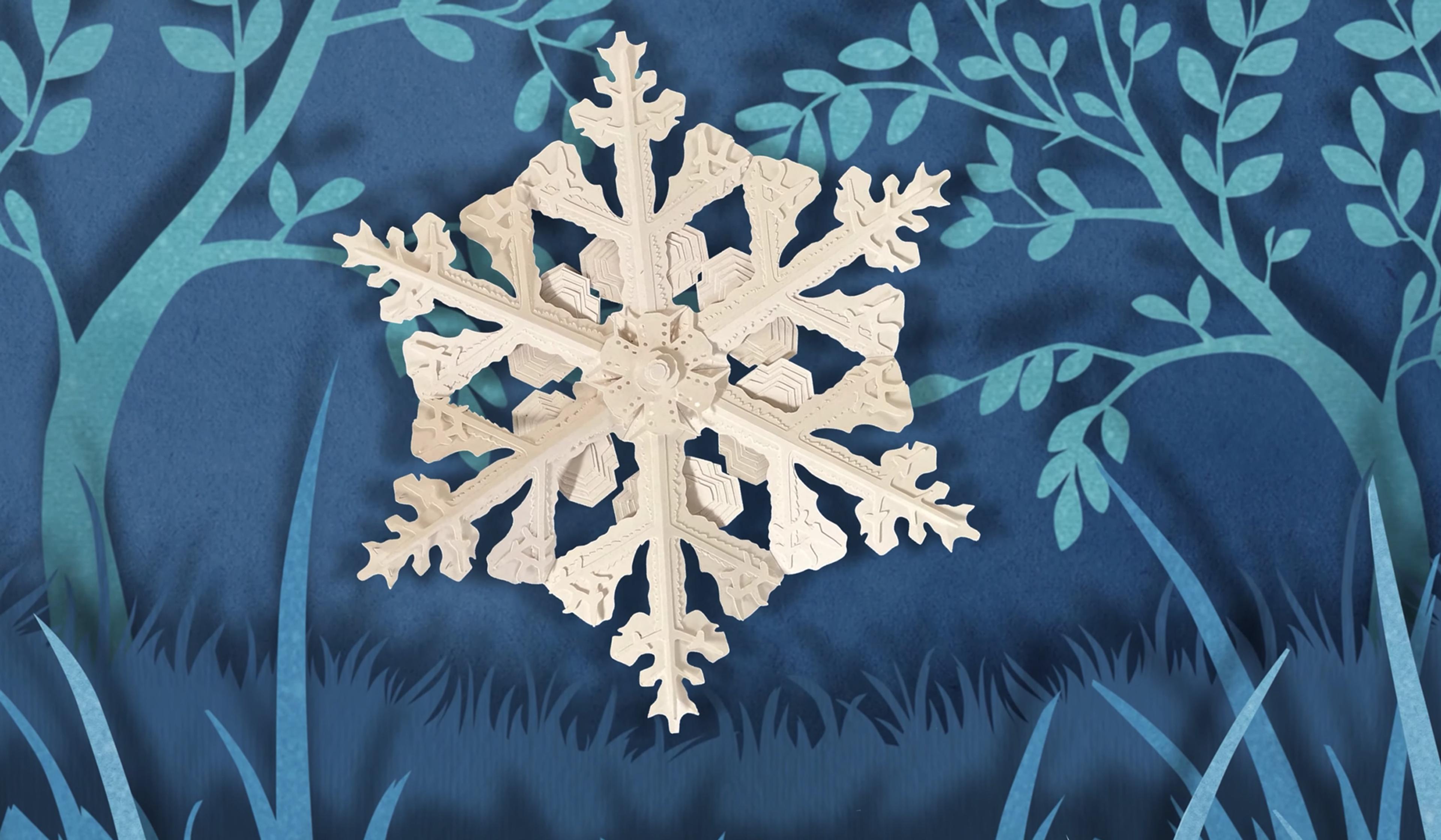 An intricate paper snowflake cutout against a dark blue background with stylised trees and grass.