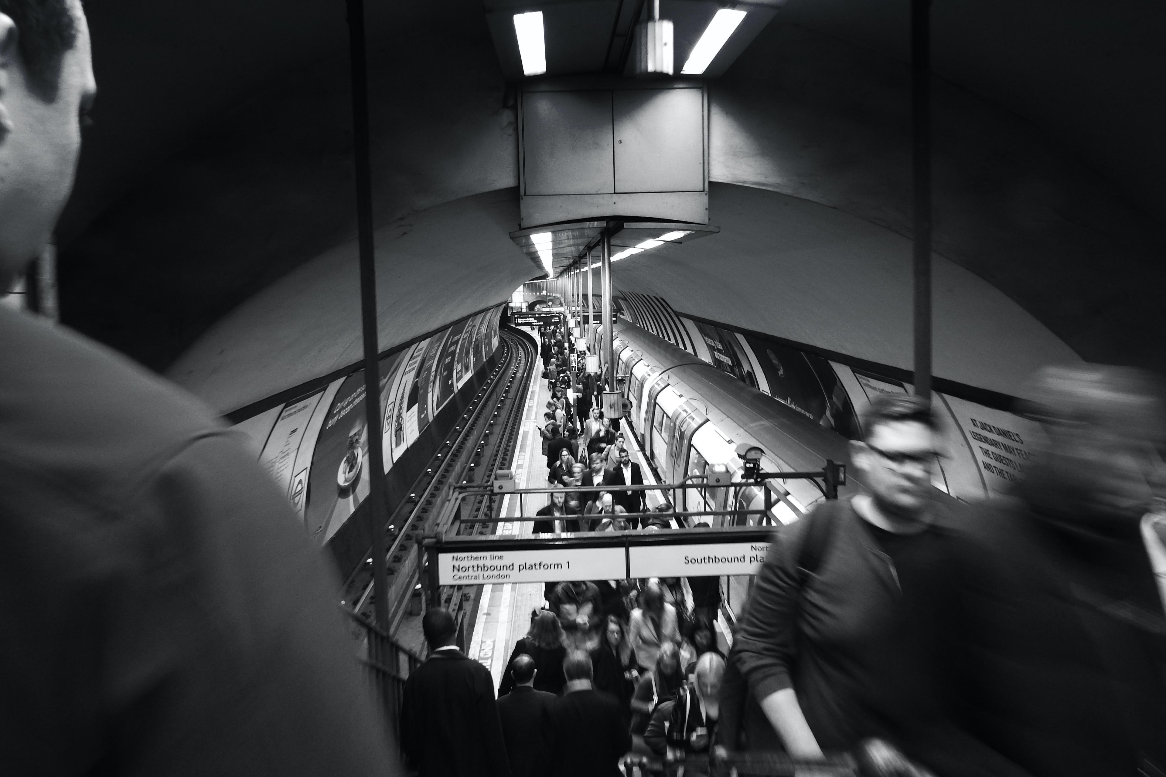 Black and white photo of a busy underground station with people and a train on the platform.