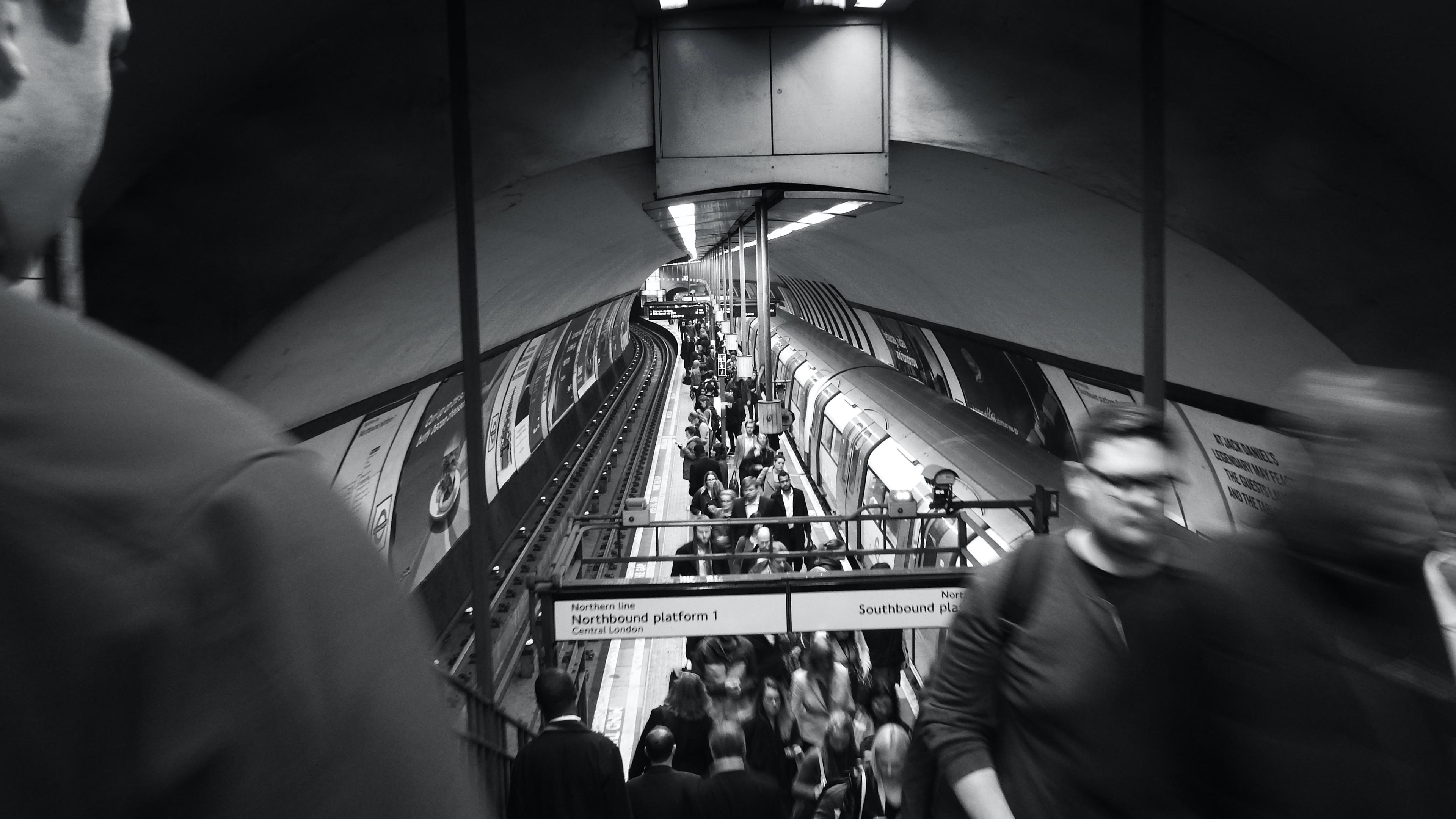 Black and white photo of a busy underground station with people and a train on the platform.