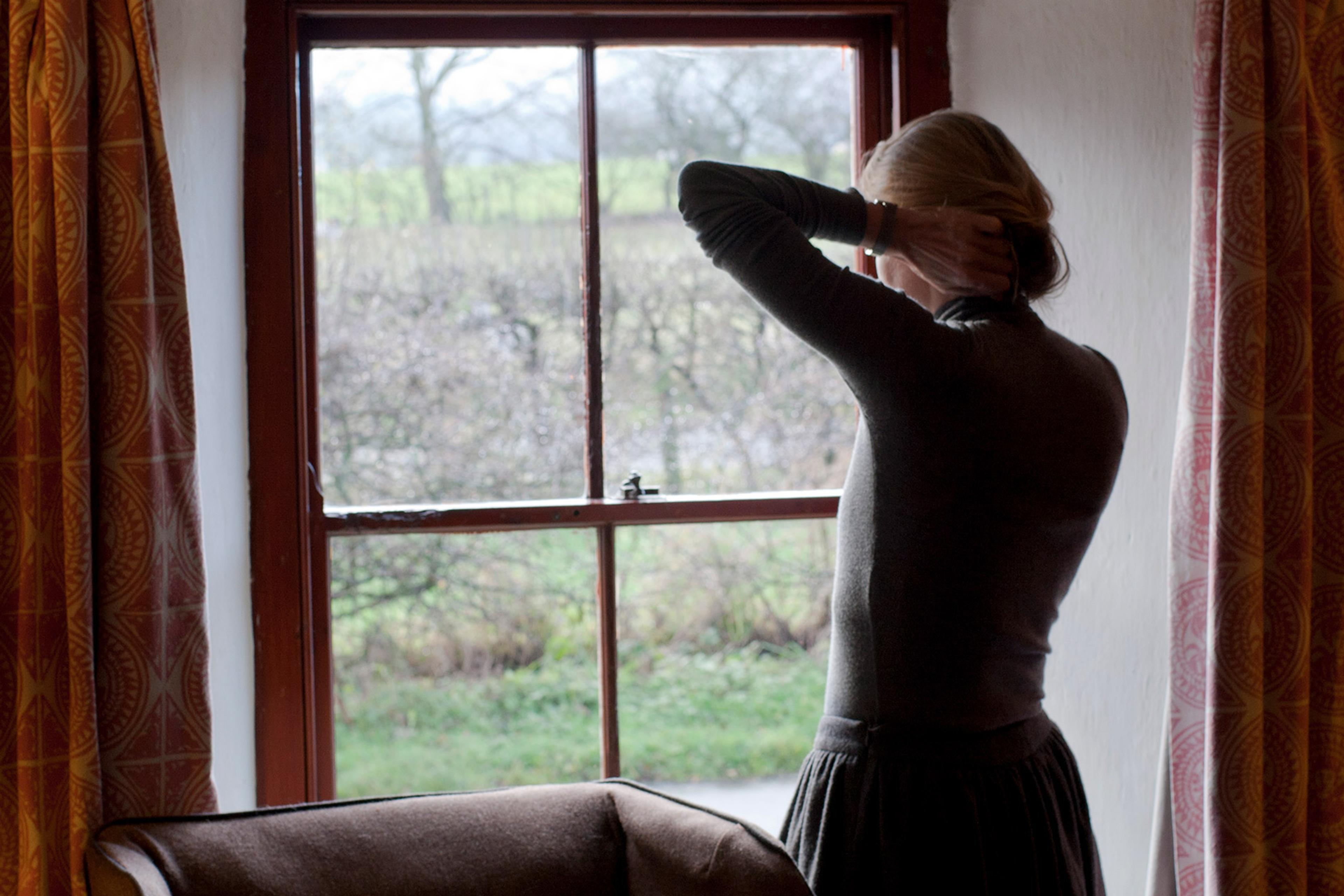 A woman seen from behind talks on a mobile phone while distractedly running her hand through her hair