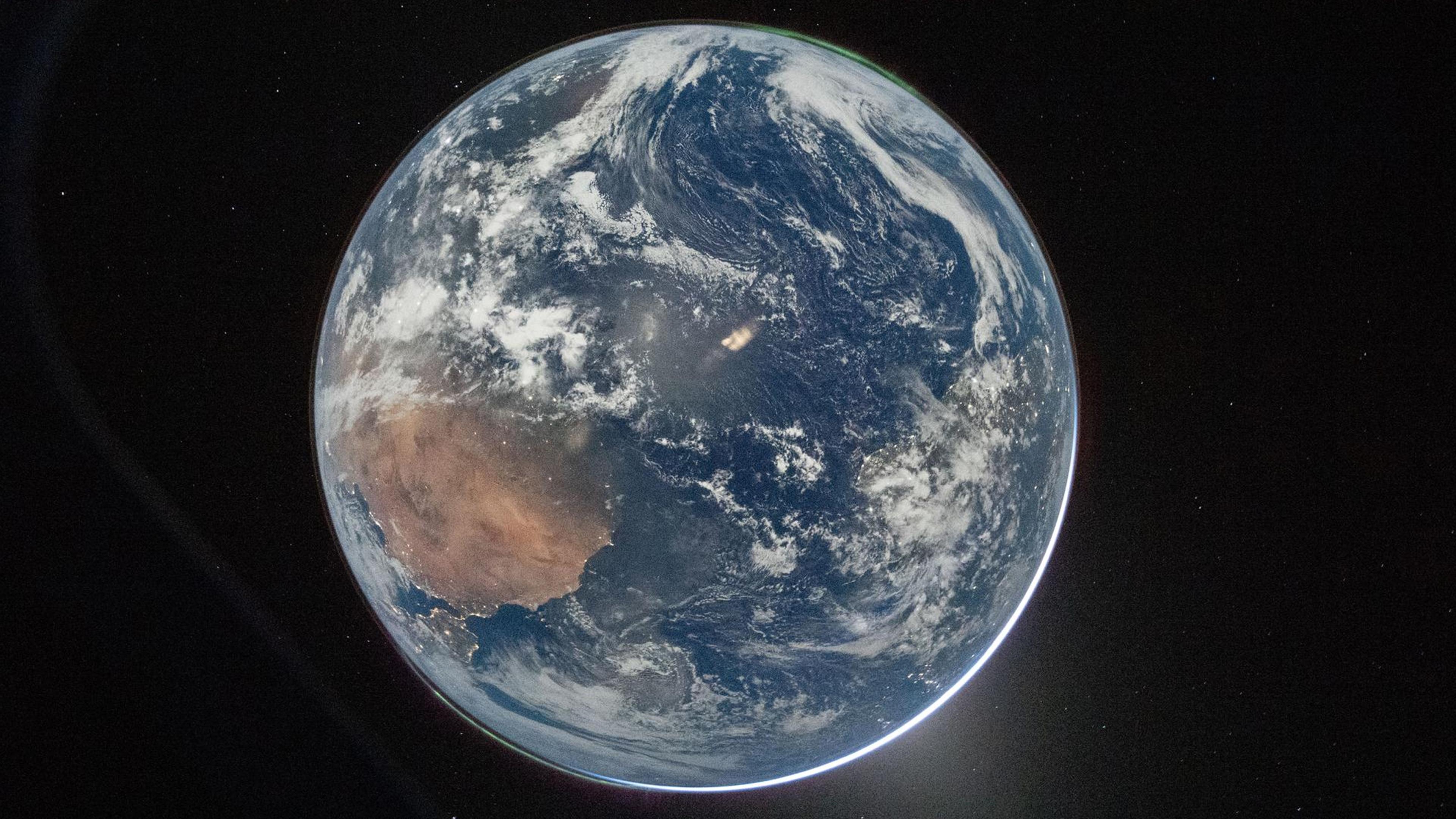 Photo of Earth from space showing clouds, oceans and land masses against a starry black background.
