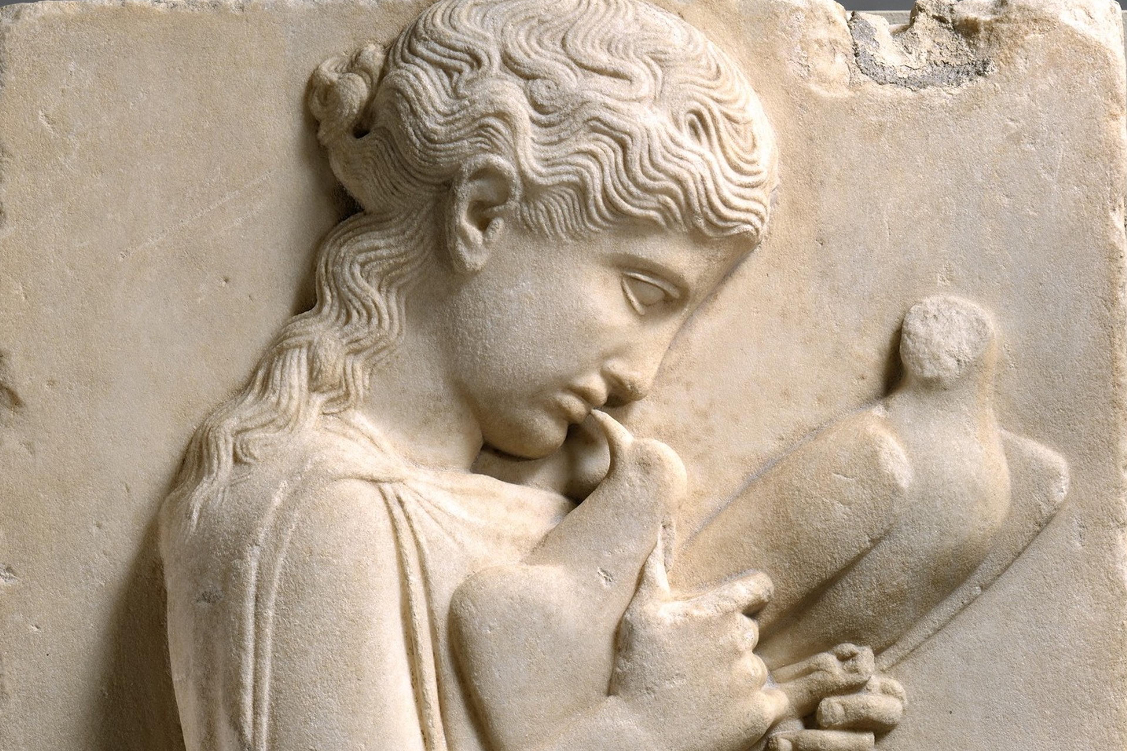 Ancient Greek marble relief of a girl holding doves, displayed on a pedestal, depicting detailed clothing and serene expression.