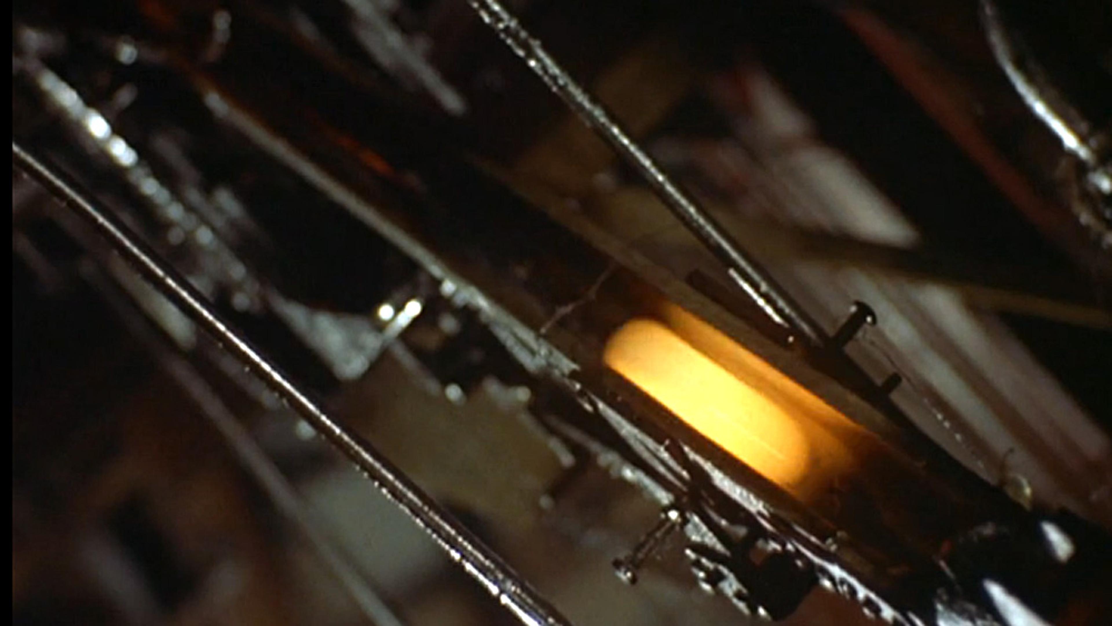 Close-up mechanical parts with a yellow light in the centre; the background is dark and out of focus.