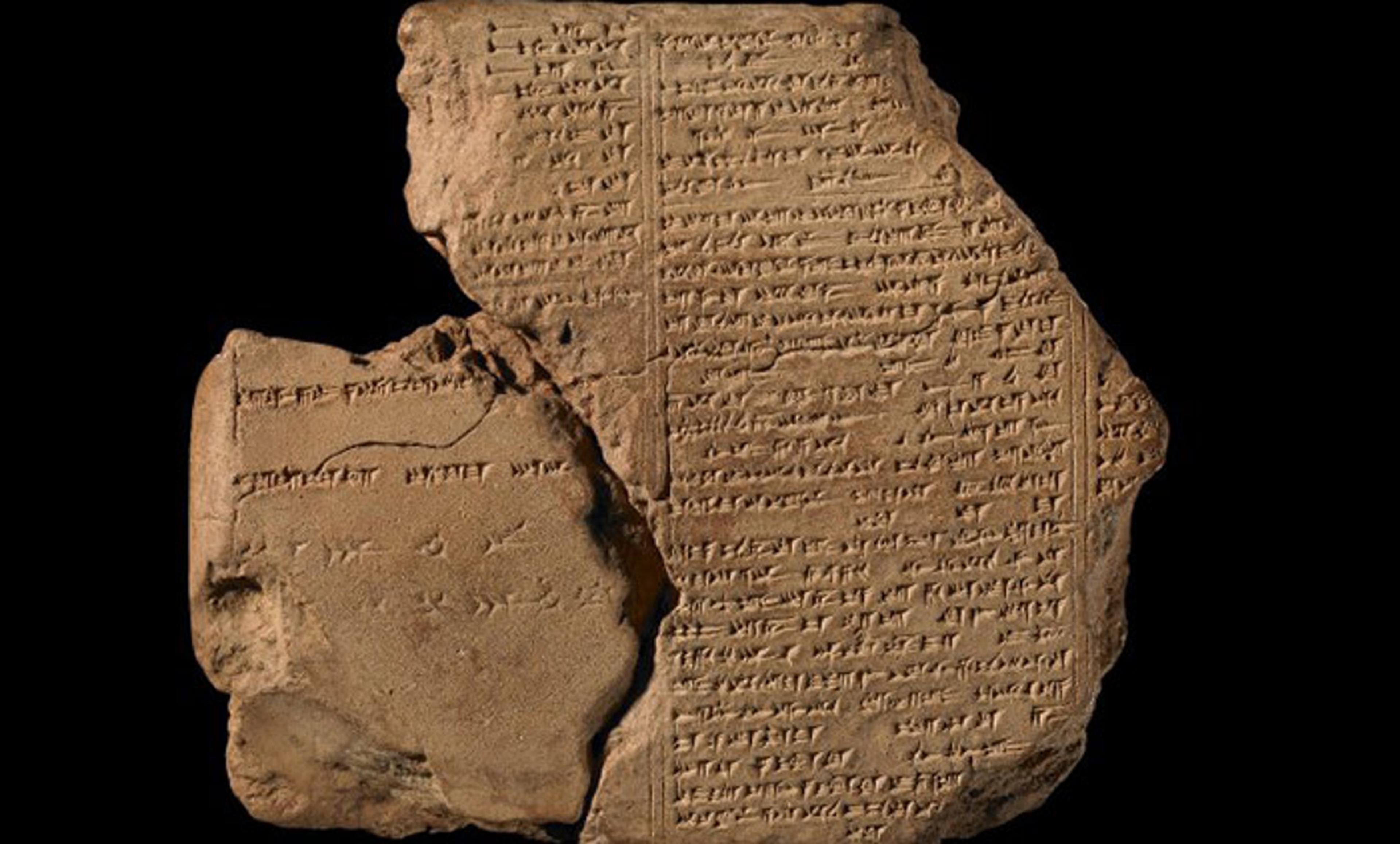 An ancient clay tablet bearing cuneiform script, photographed against a black background. The tablet is broken into two pieces.