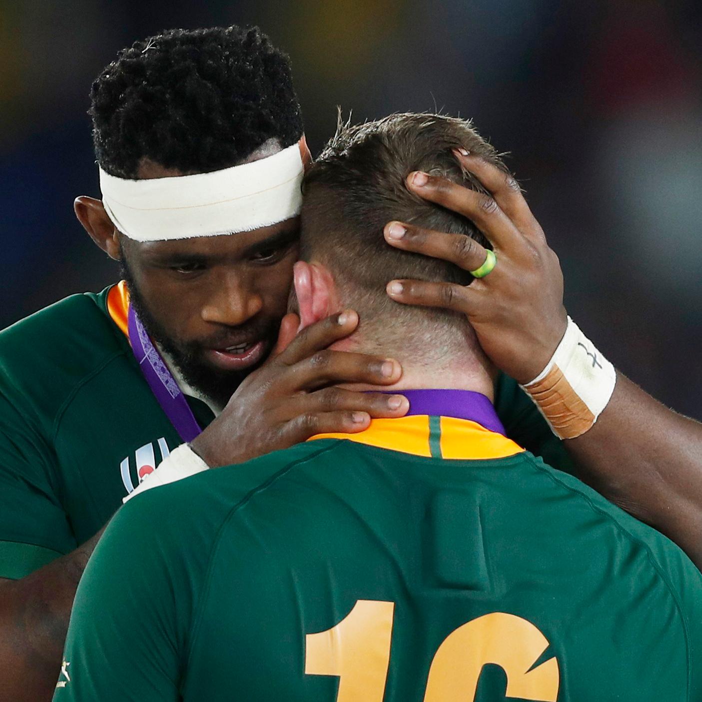 A rugby player embracing one of his teammates.