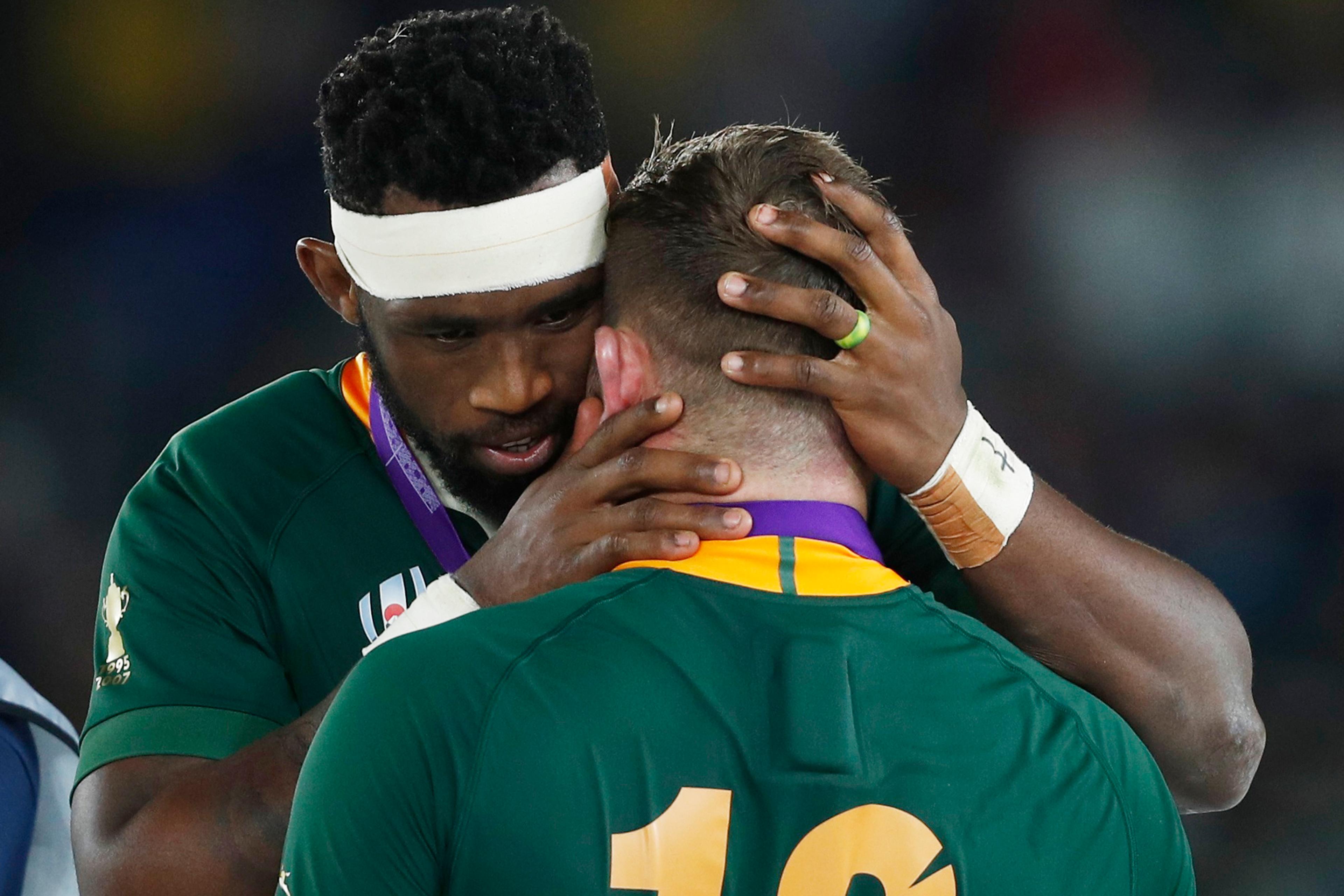 A rugby player embracing one of his teammates.