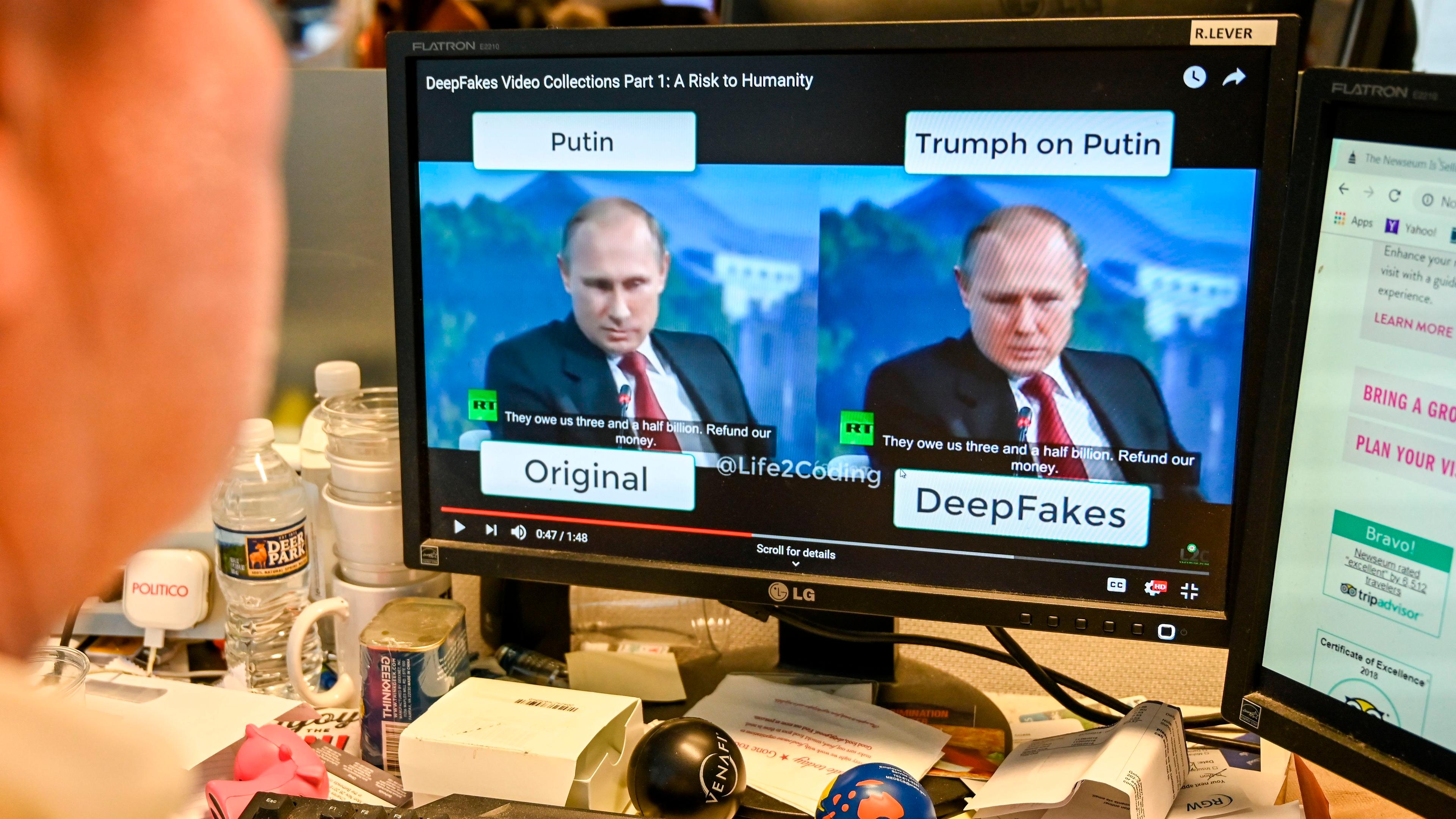 Photo of a computer screen showing a deepfake video comparison with original content on a cluttered desk.