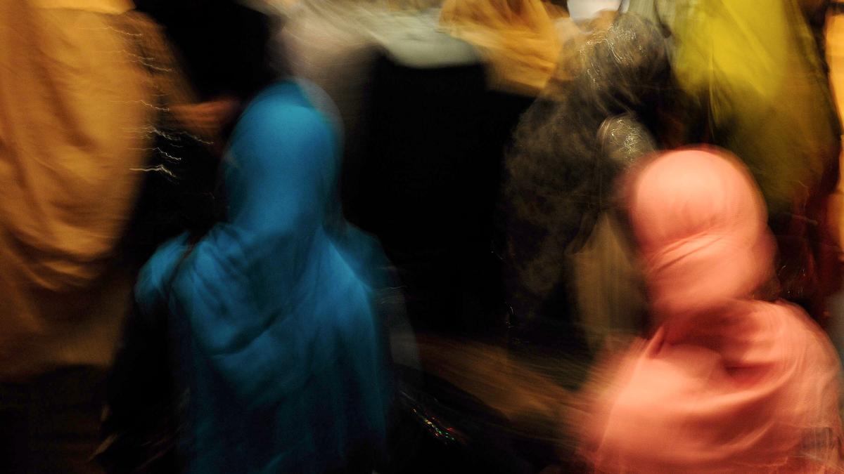 Abstract photo of people blurred in motion wearing colourful hijabs; colours include blue, pink and yellow.