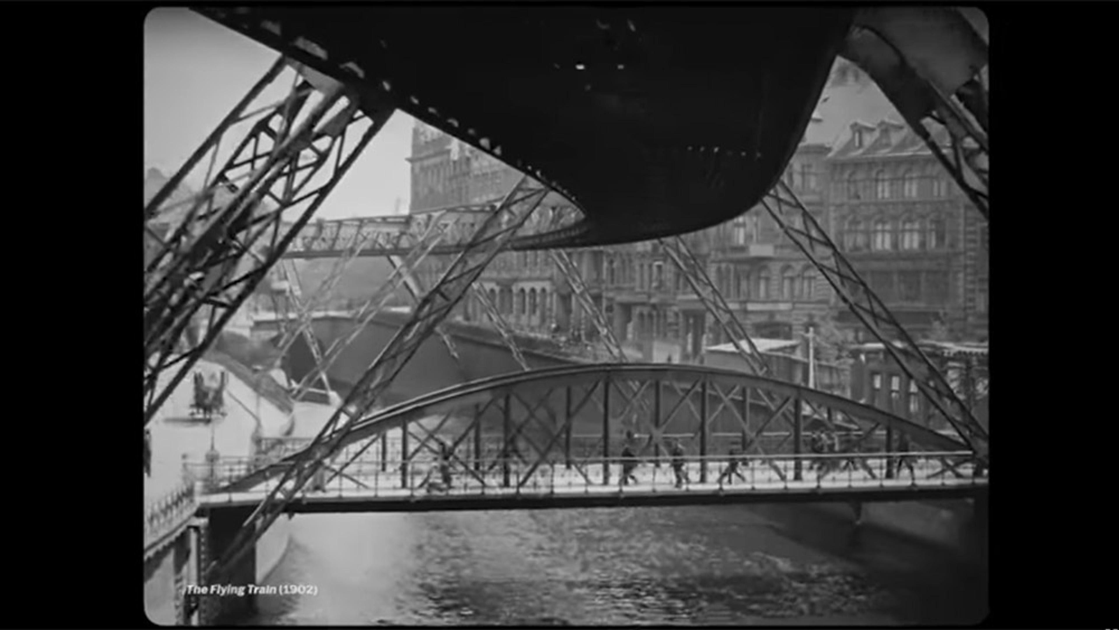 Black-and-white photo of a historic cityscape featuring multiple bridges and elevated train tracks over a river.