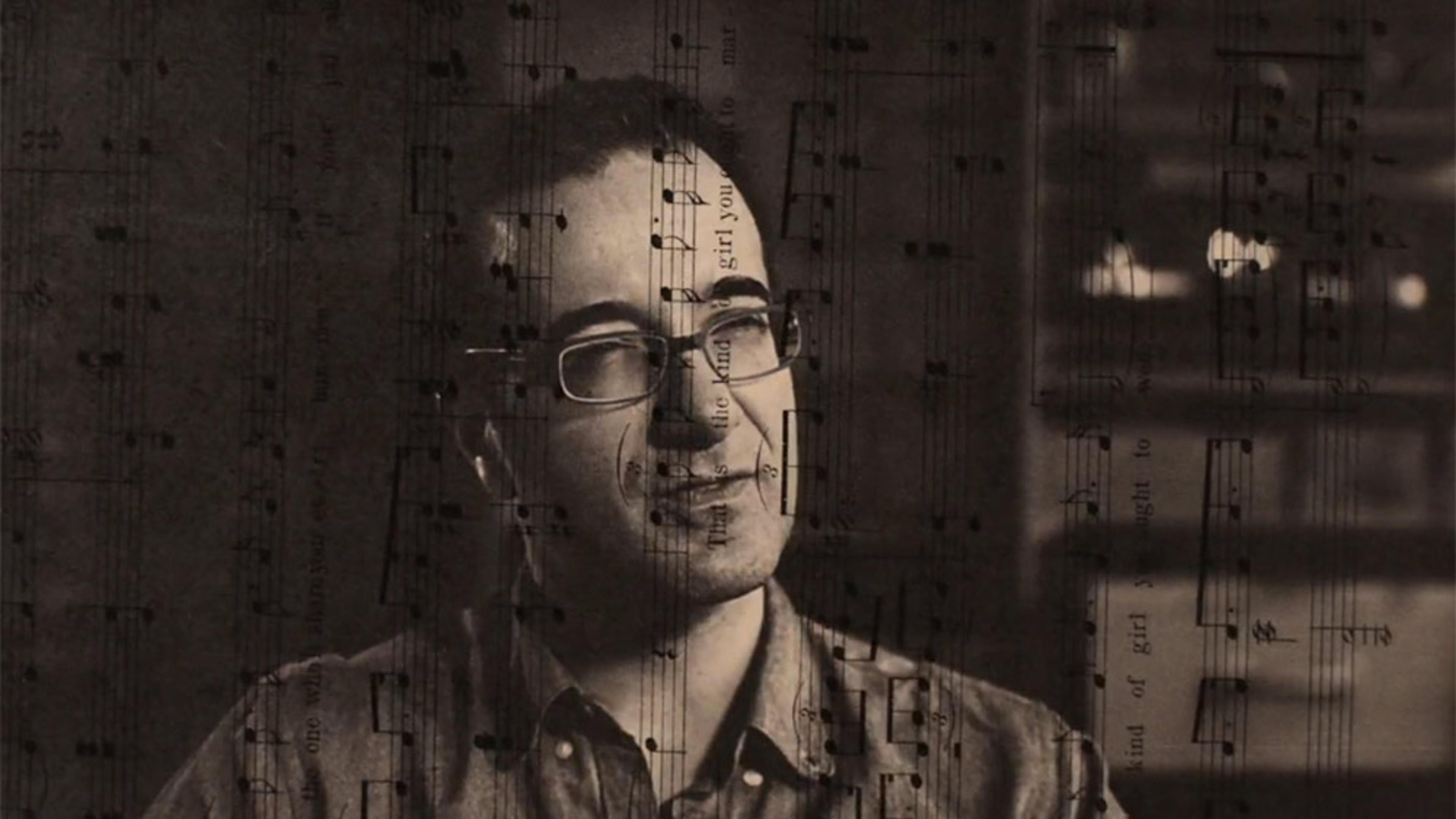 A man with glasses overlaid with sheet music creating a layered effect. The background is dimly lit, adding a dramatic tone.