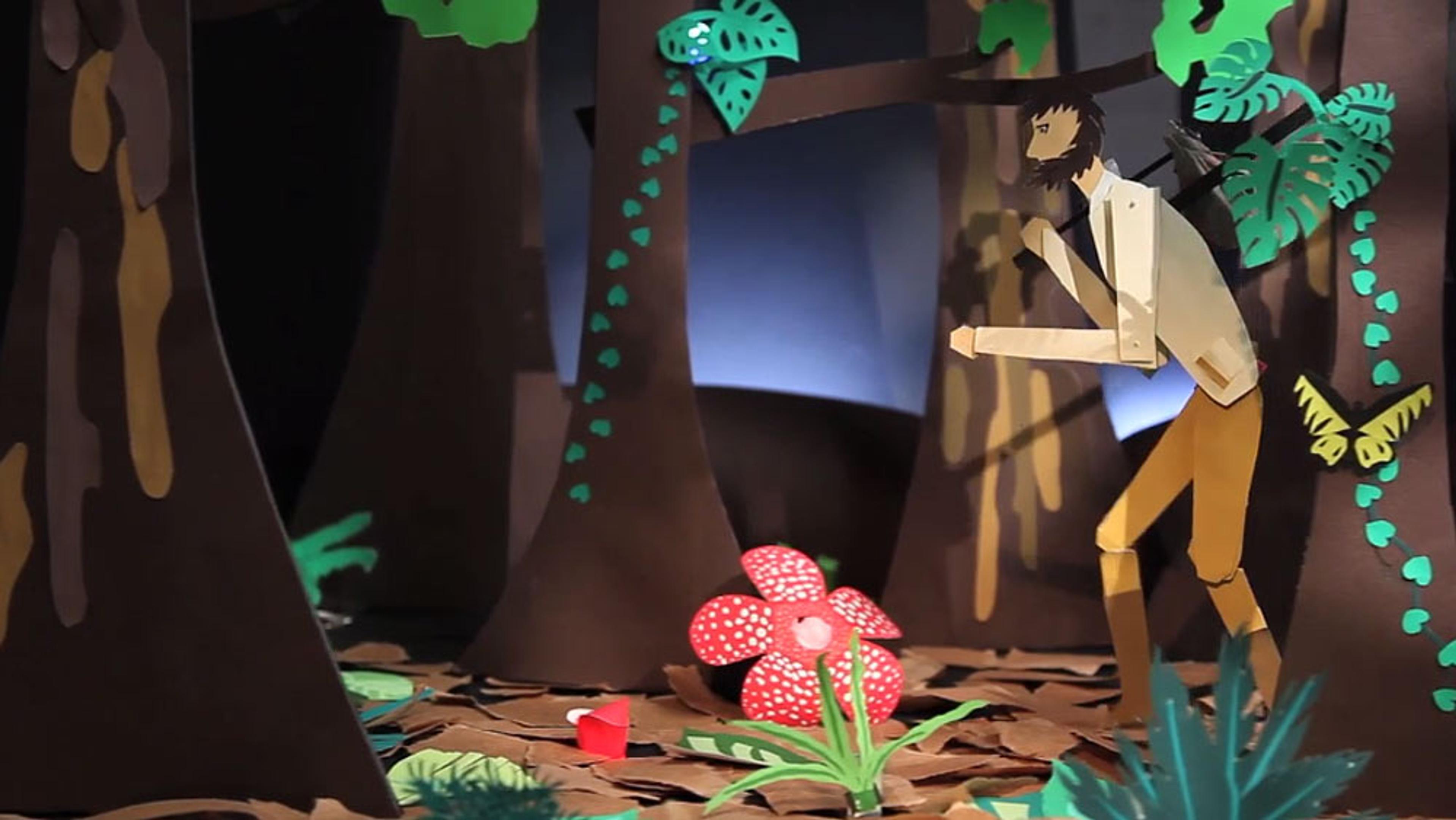 Papercraft artwork of a bearded man in a forest, looking at a large red flower with white spots, surrounded by trees and foliage.