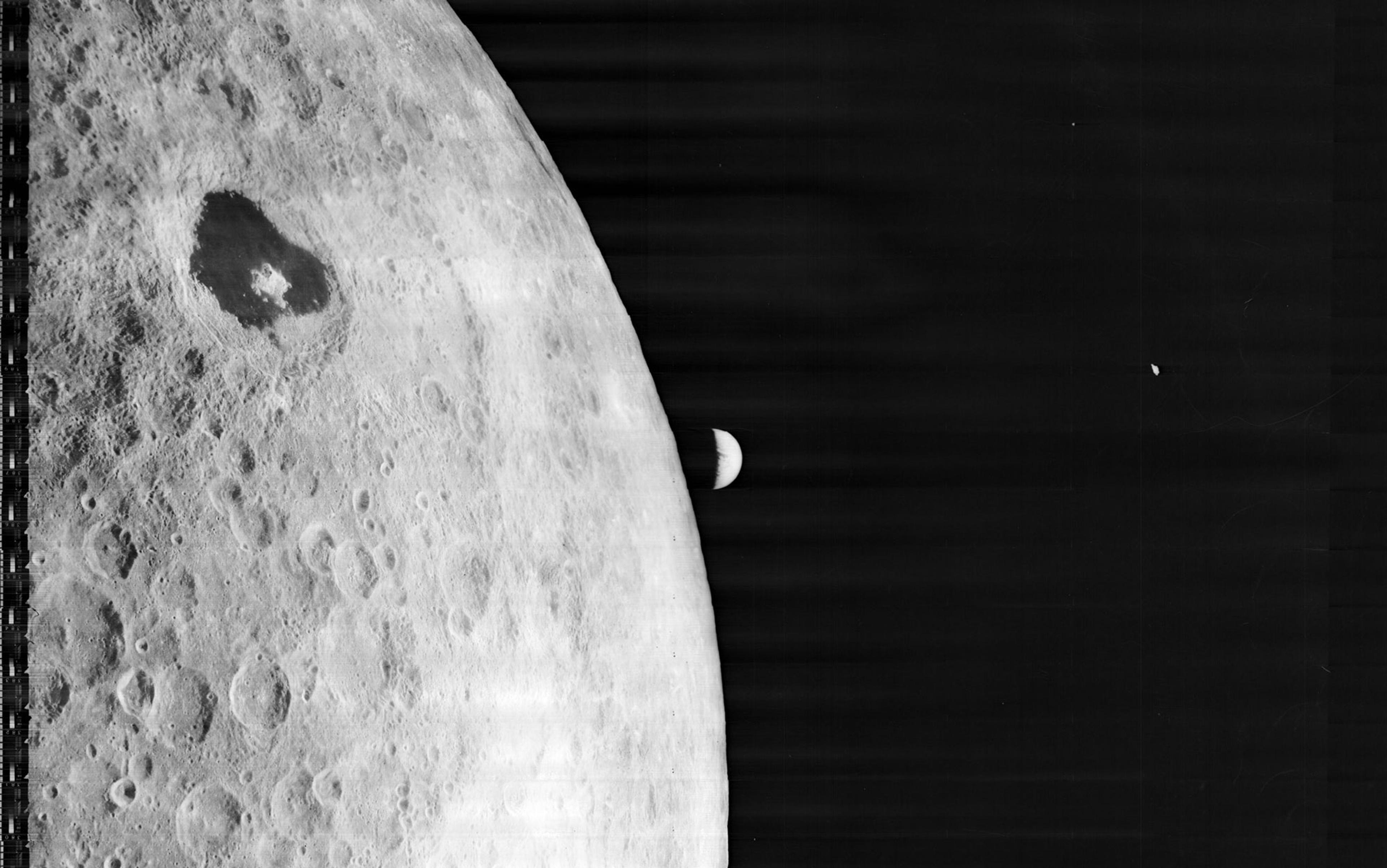 Black-and-white photo of the Moon’s surface with craters, with a distant Earth visible on the horizon in space.