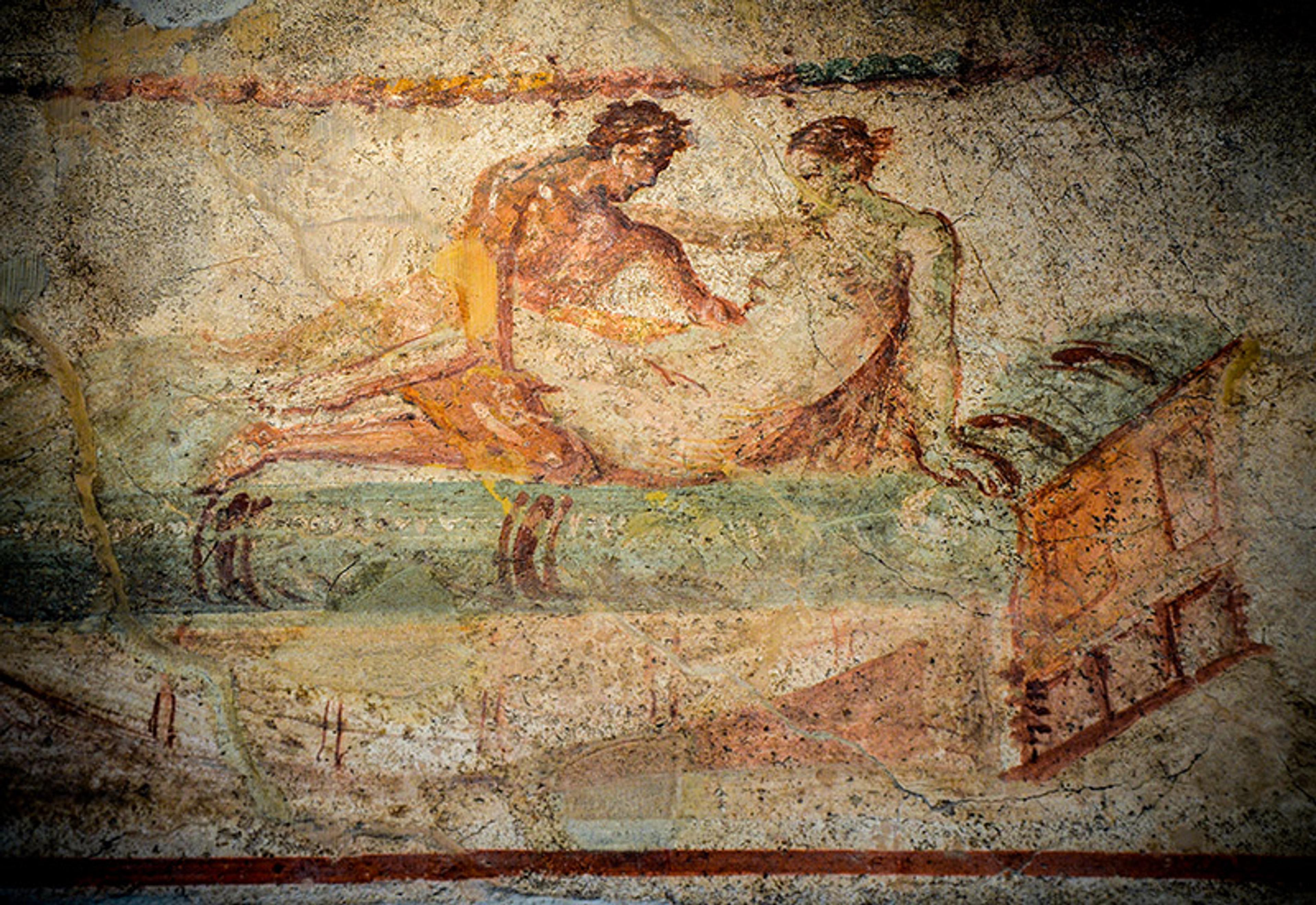 A fresco depicting a man and a woman in an intimate moment on a bed. The ancient artwork shows deteriorated paint.
