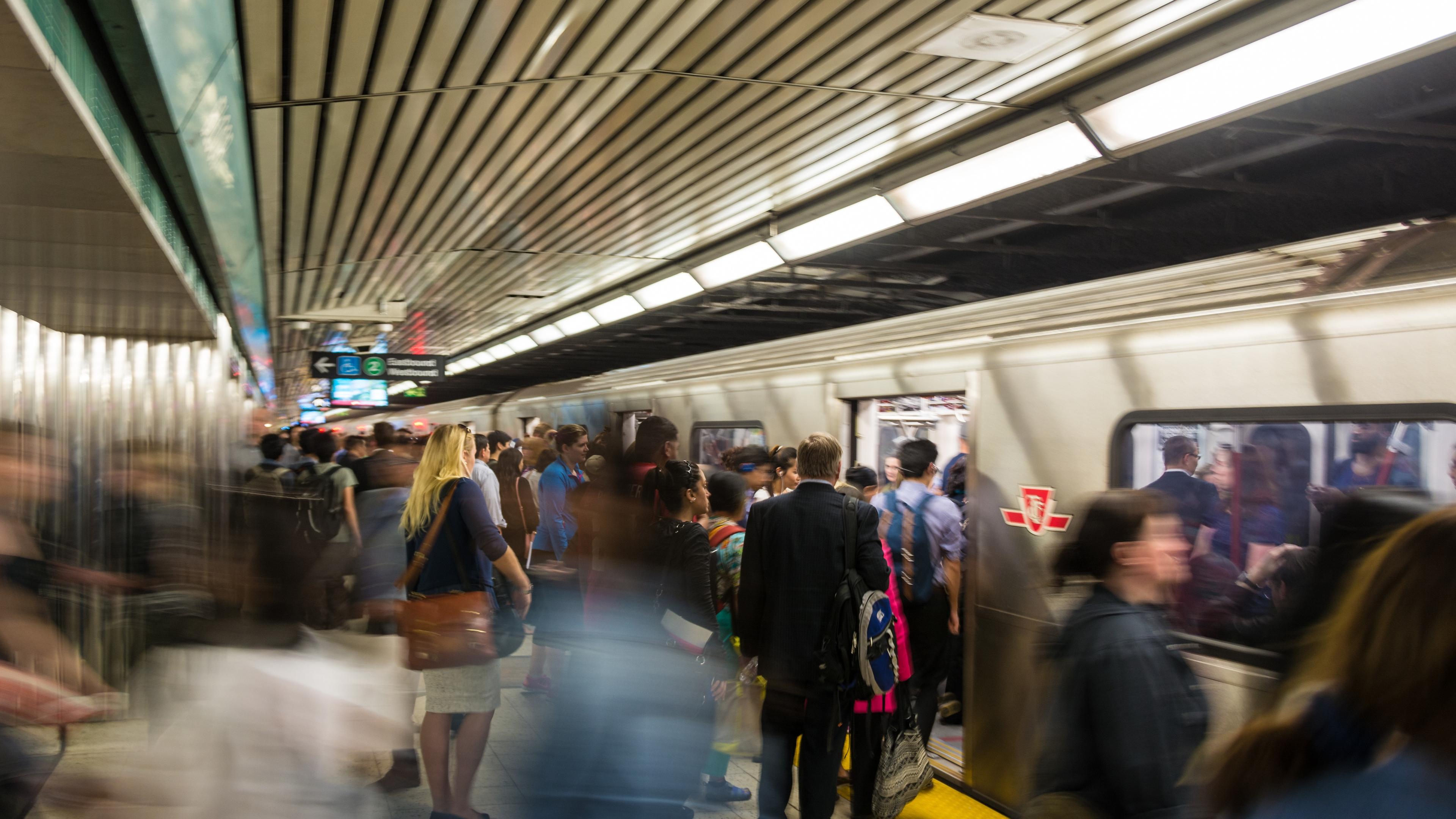 Photo of a busy underground train platform with people boarding and exiting a stationary train.