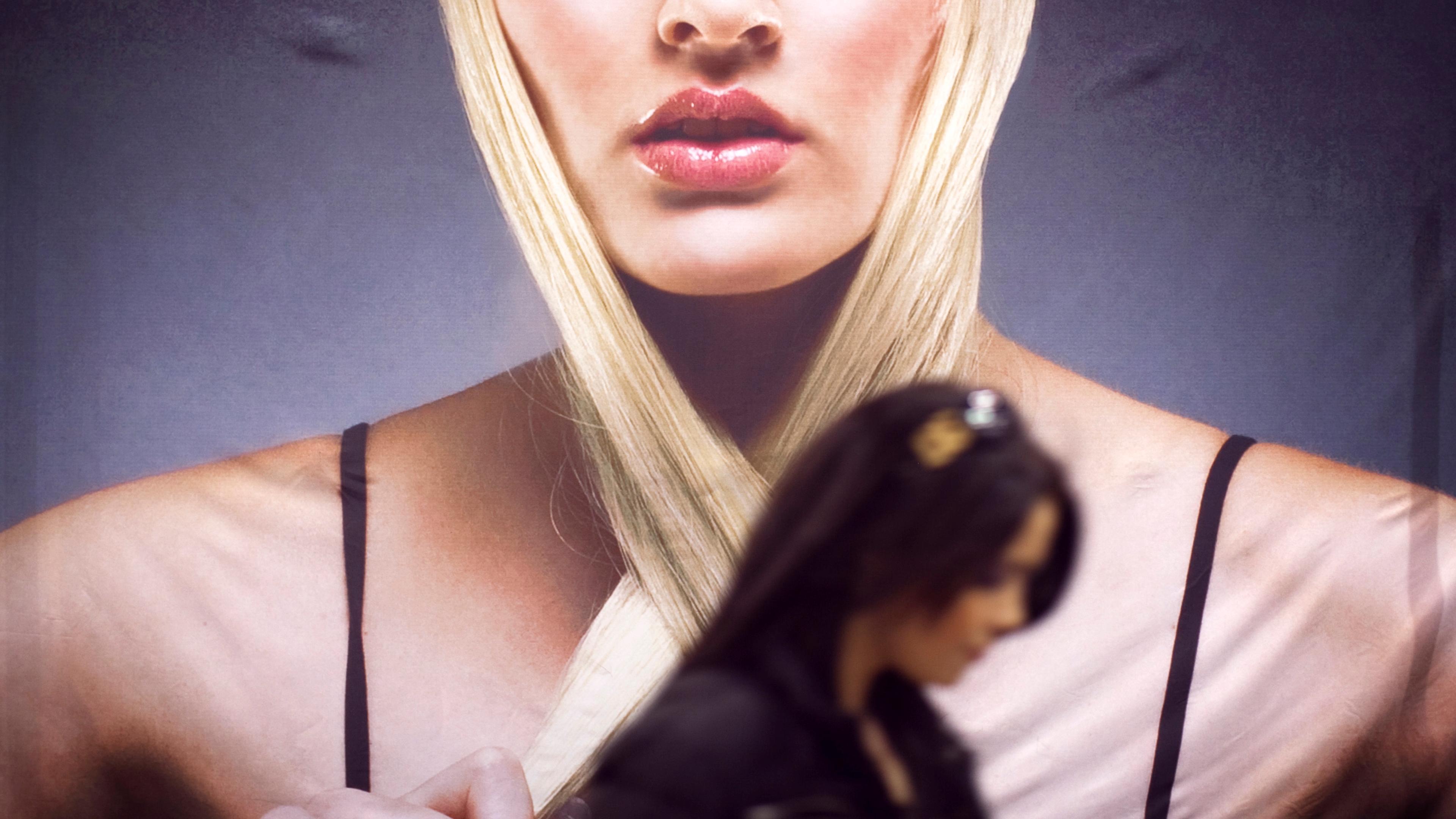 Photo of a large poster depicting a woman with blonde hair, with a person walking in the foreground.