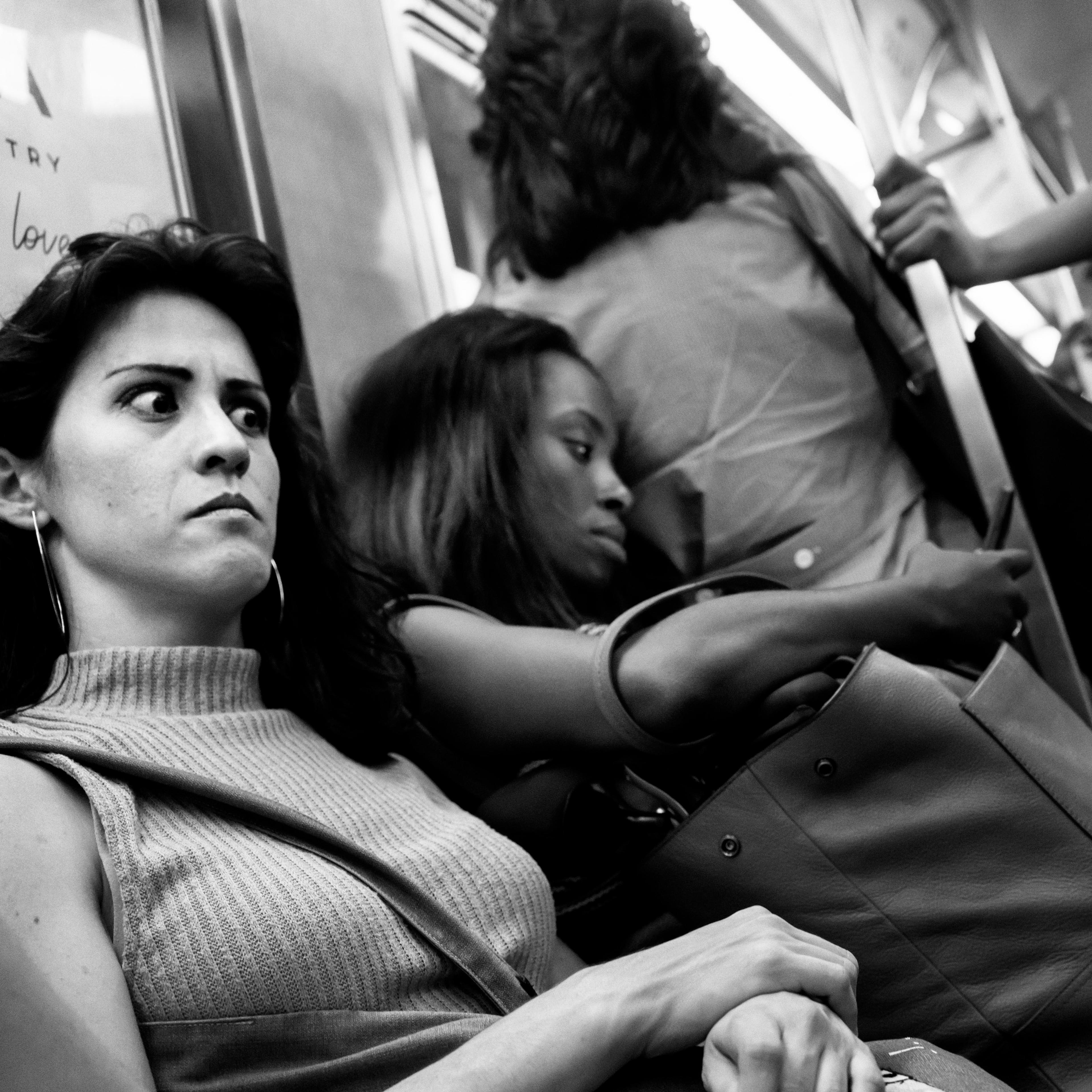 붐비는 기차 객차 안에 앉아 있거나 서 있는 승객들의 흑백 사진. 어떤 승객들은 가방과 꽃을 들고 있다.<BR> 앞쪽에 앉아 있는 한 여성의 얼굴에는 짜증스러운 표정이 깃들어 있다.<BR>