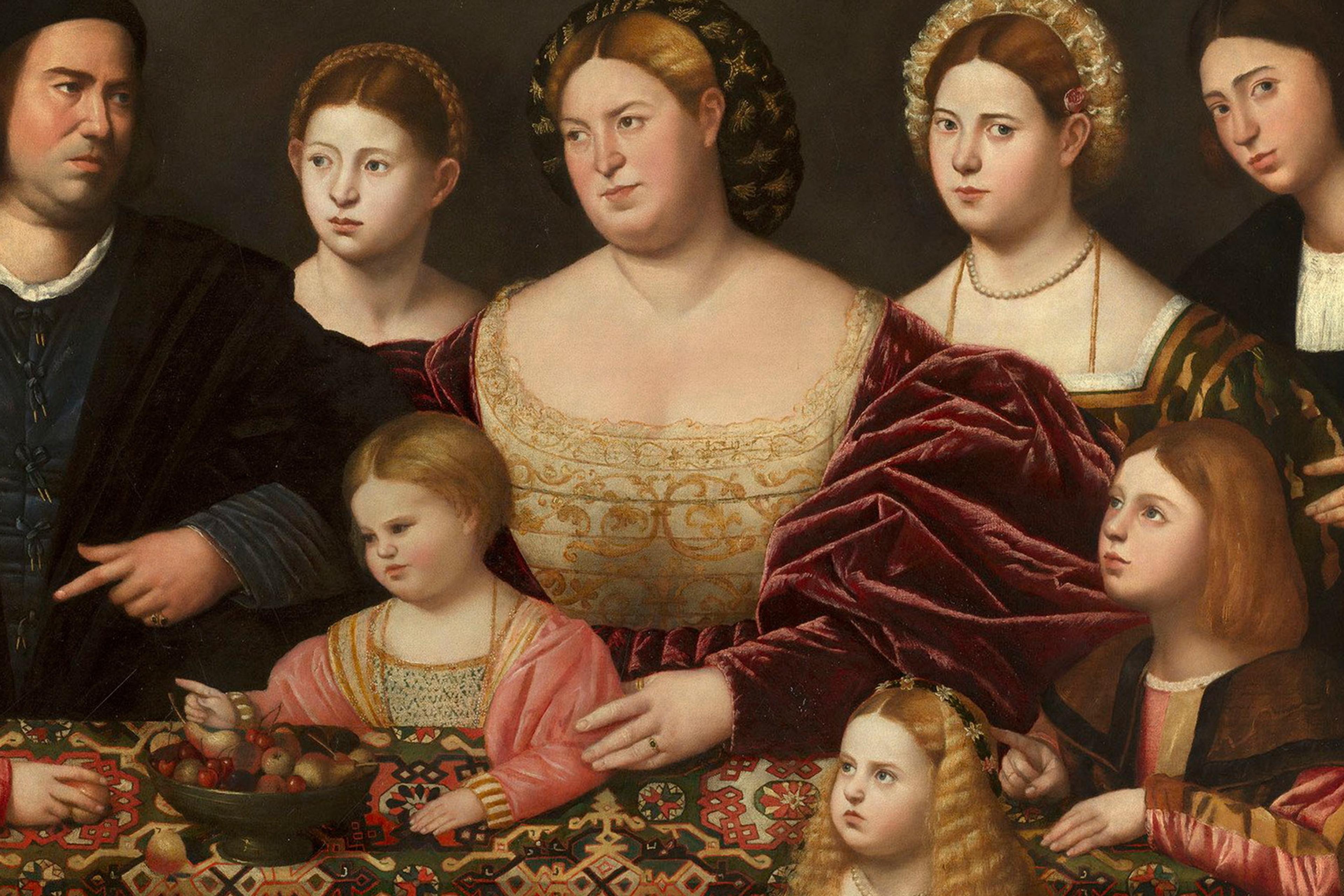 Painting of a Renaissance family gathered around a table with a patterned cloth and fruit bowl, showcasing rich attire and expressions.