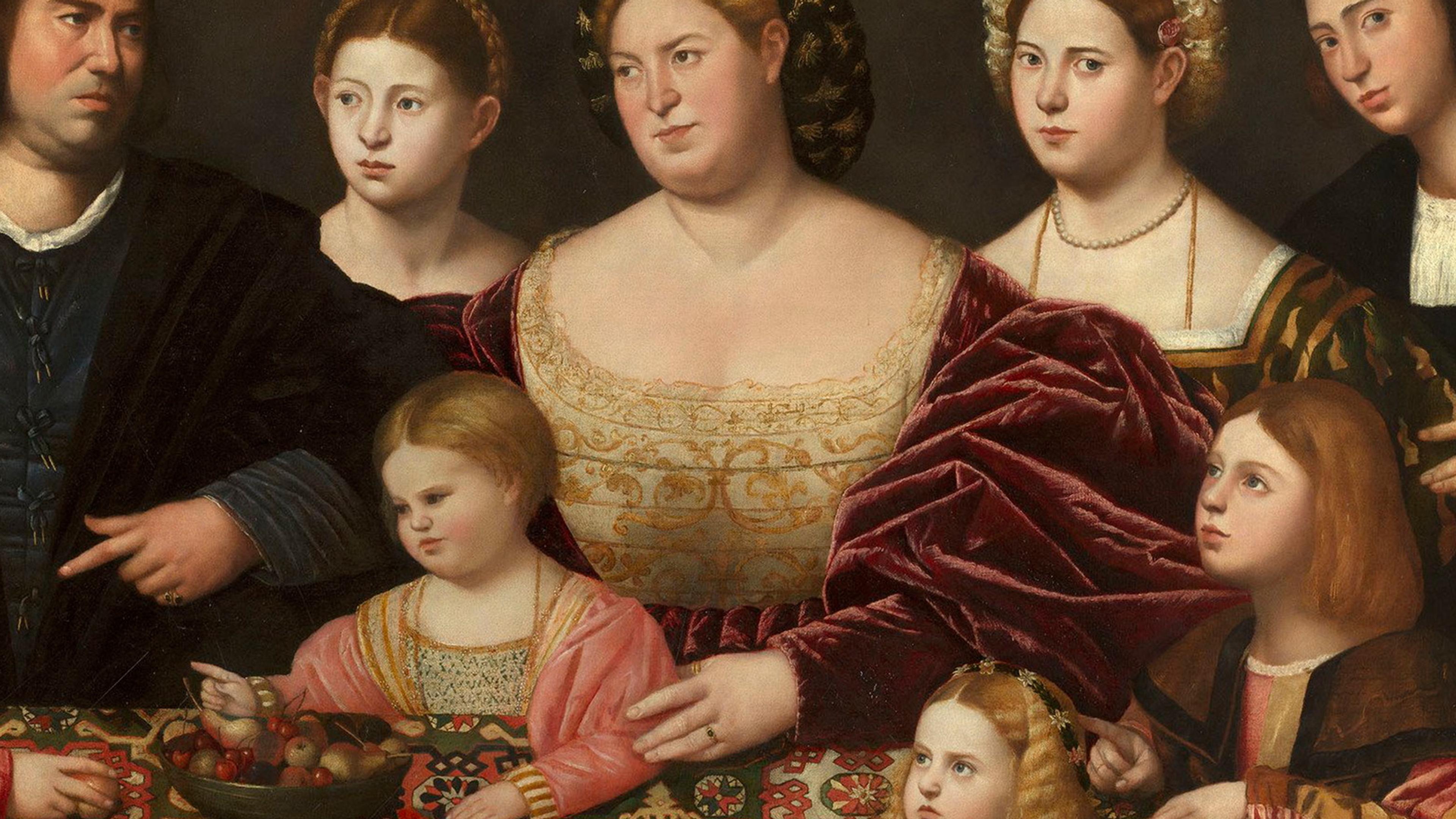 Painting of a Renaissance family gathered around a table with a patterned cloth and fruit bowl, showcasing rich attire and expressions.