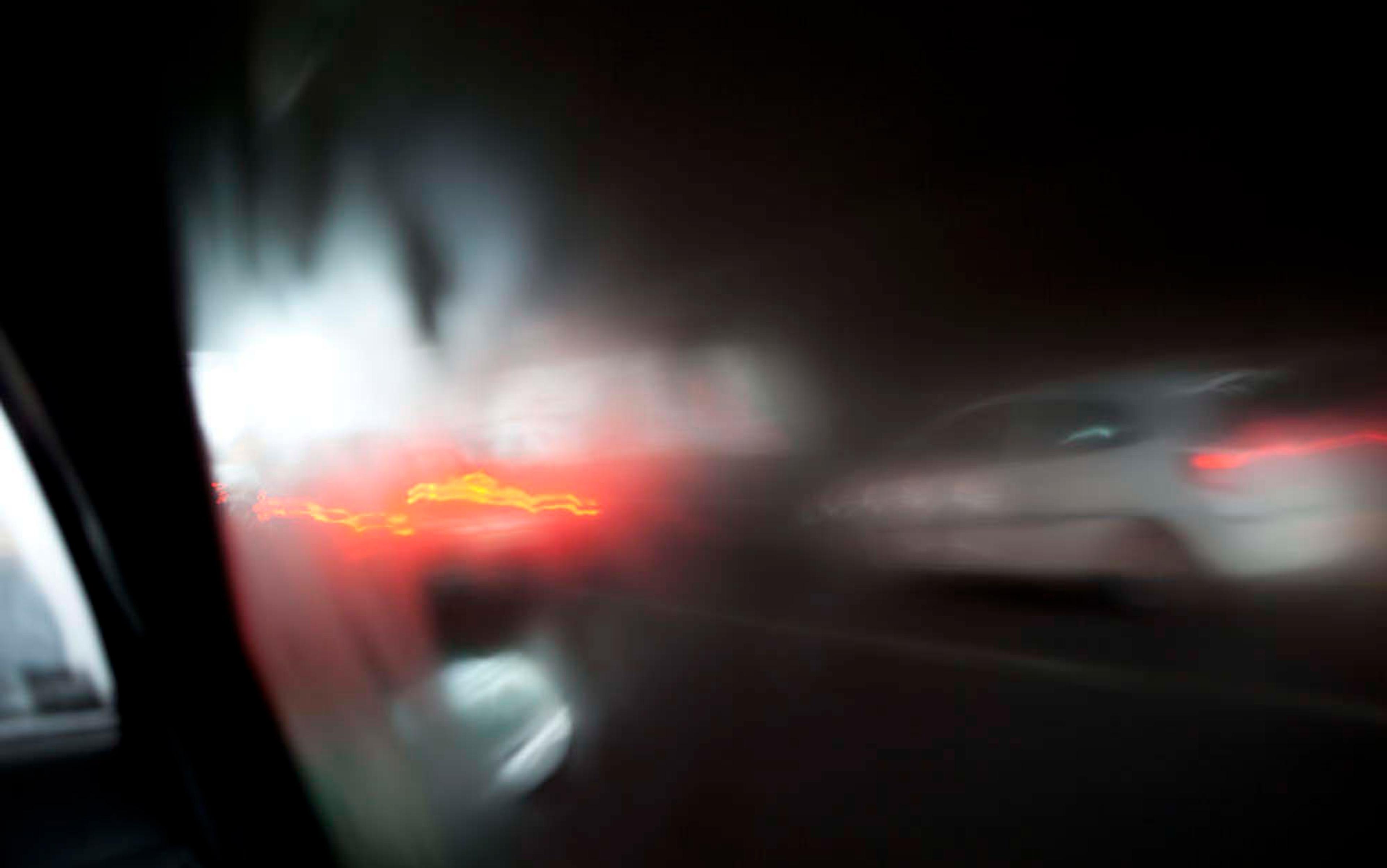 A blurred view through a car window at night with distorted bright lights