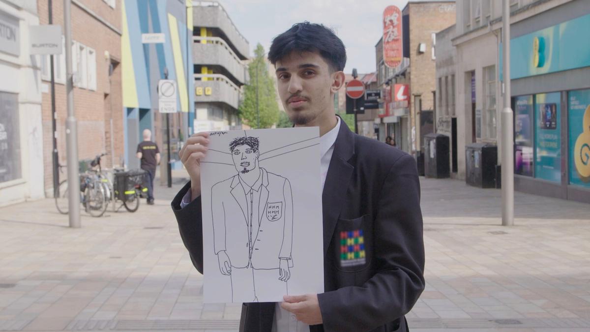 Photo of a man holding a hand-drawn sketch of himself on a city street, wearing a blazer with a colourful patch.