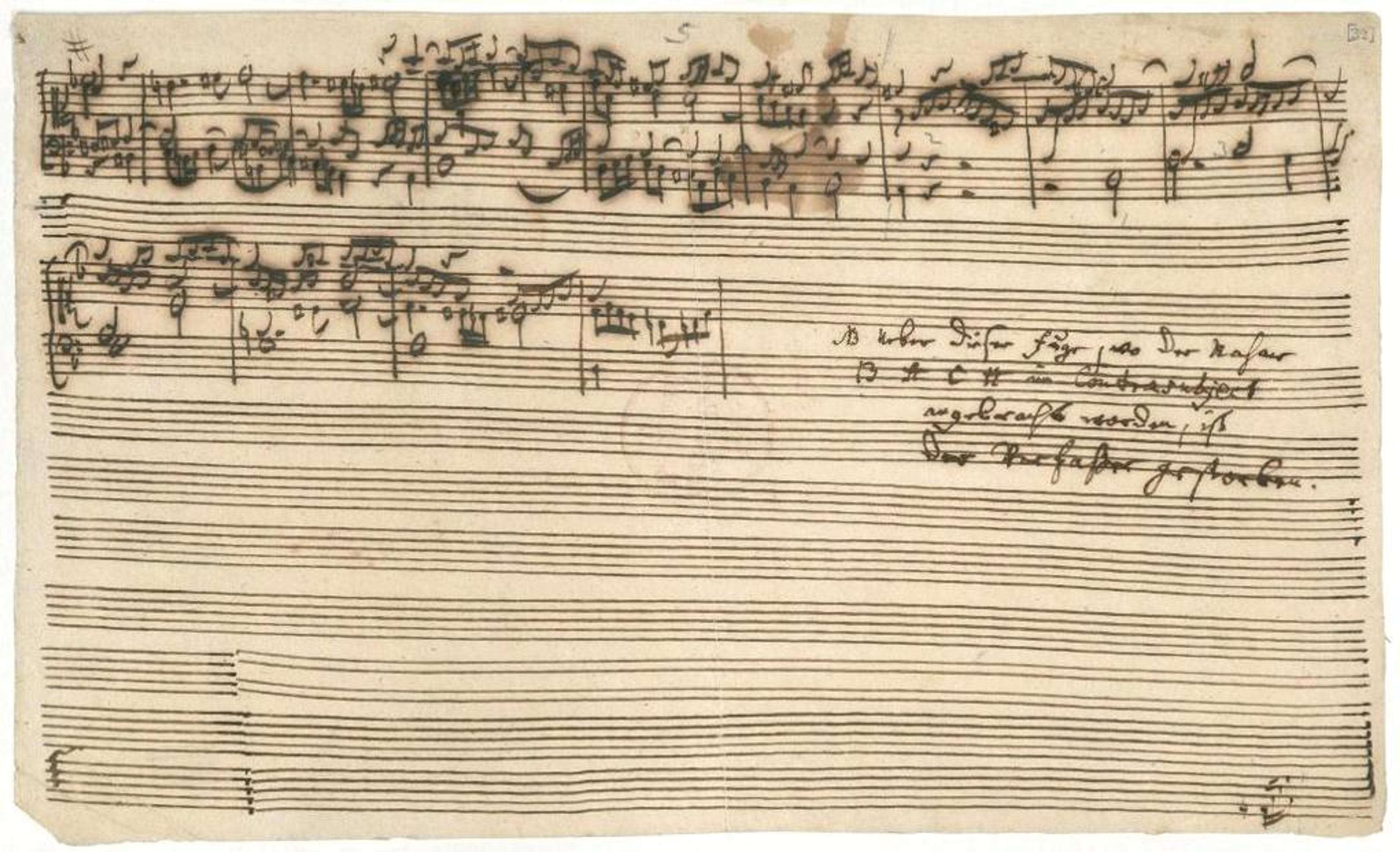 Handwritten musical score on yellowed manuscript paper with several lines of text written in German; some ink smudges are visible.