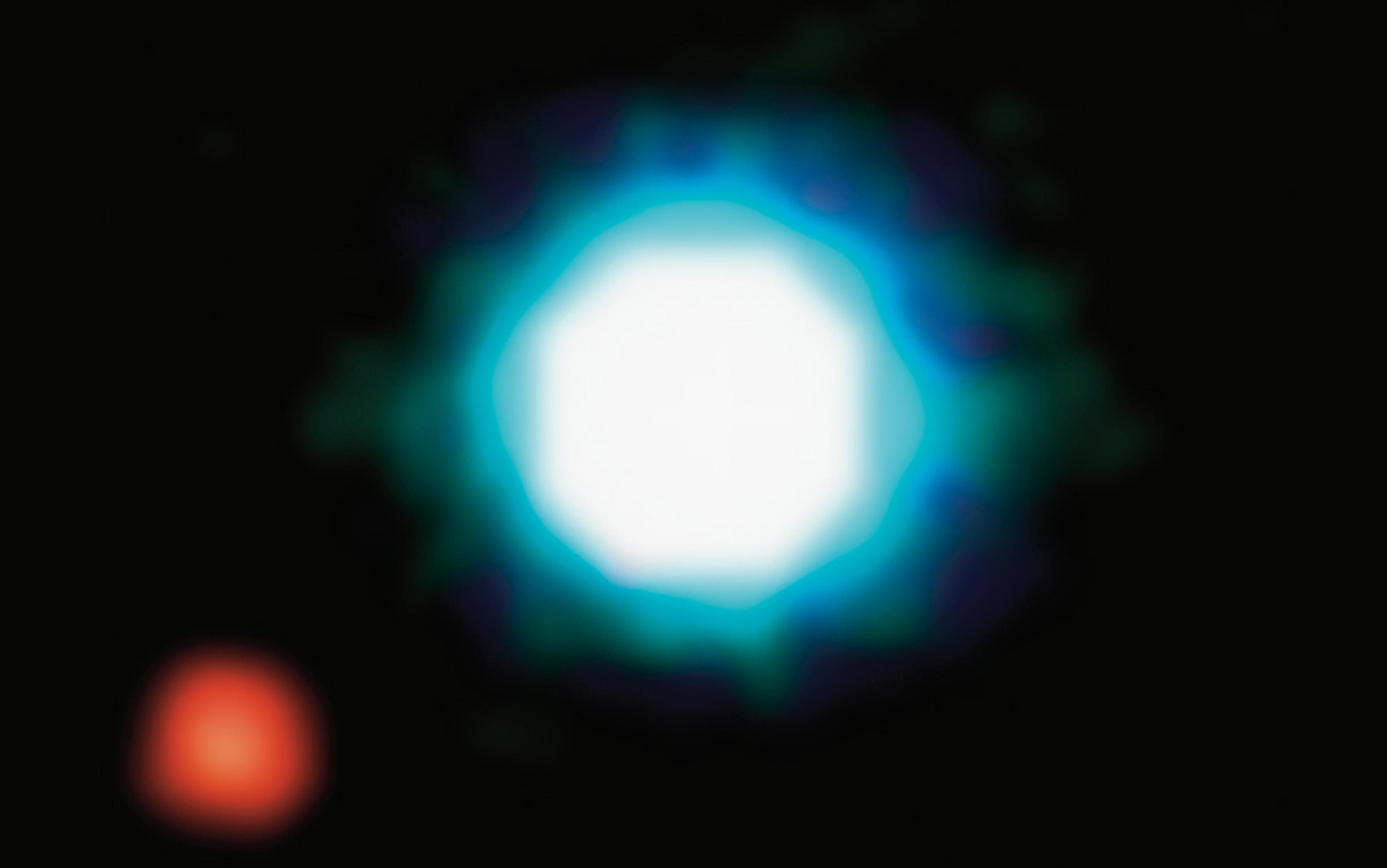 Bright white and turquoise circular light with a smaller red spot on a black background.