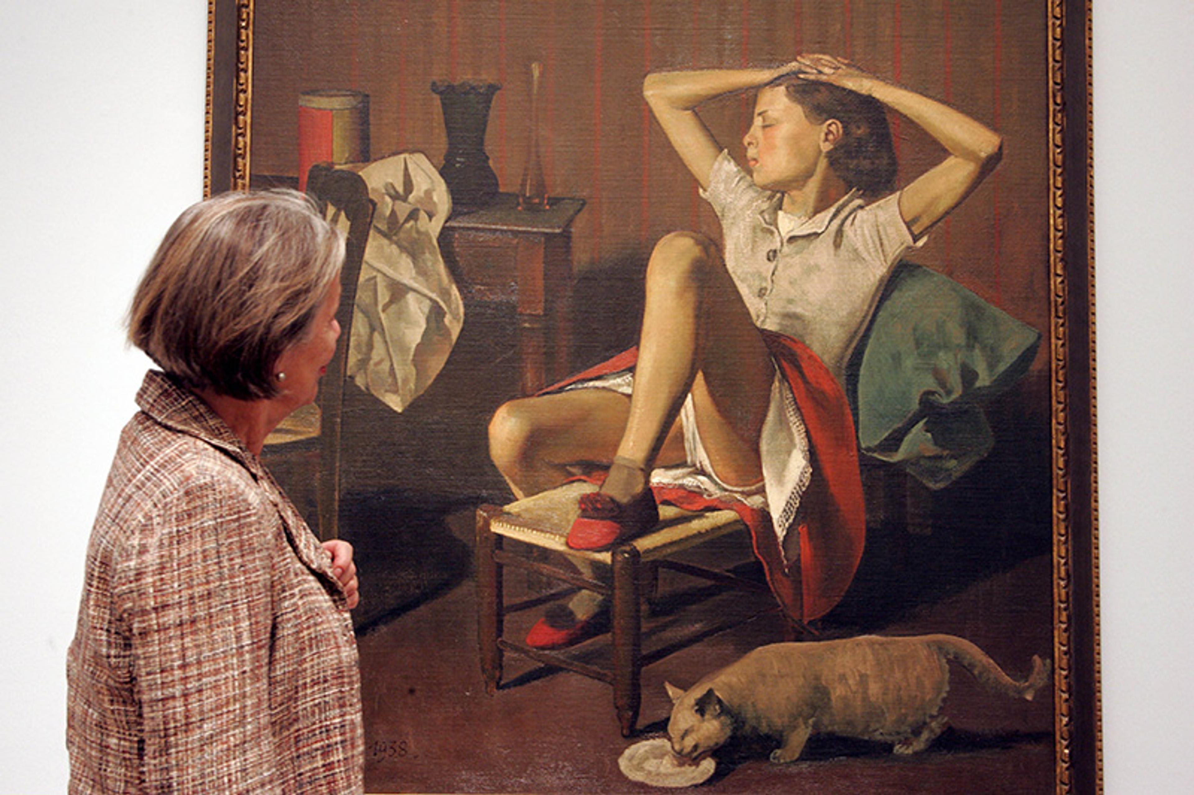 An older woman observing a painting of a young girl sitting with her leg raised and her underwear exposed, with a cat licking a bowl at her feet.