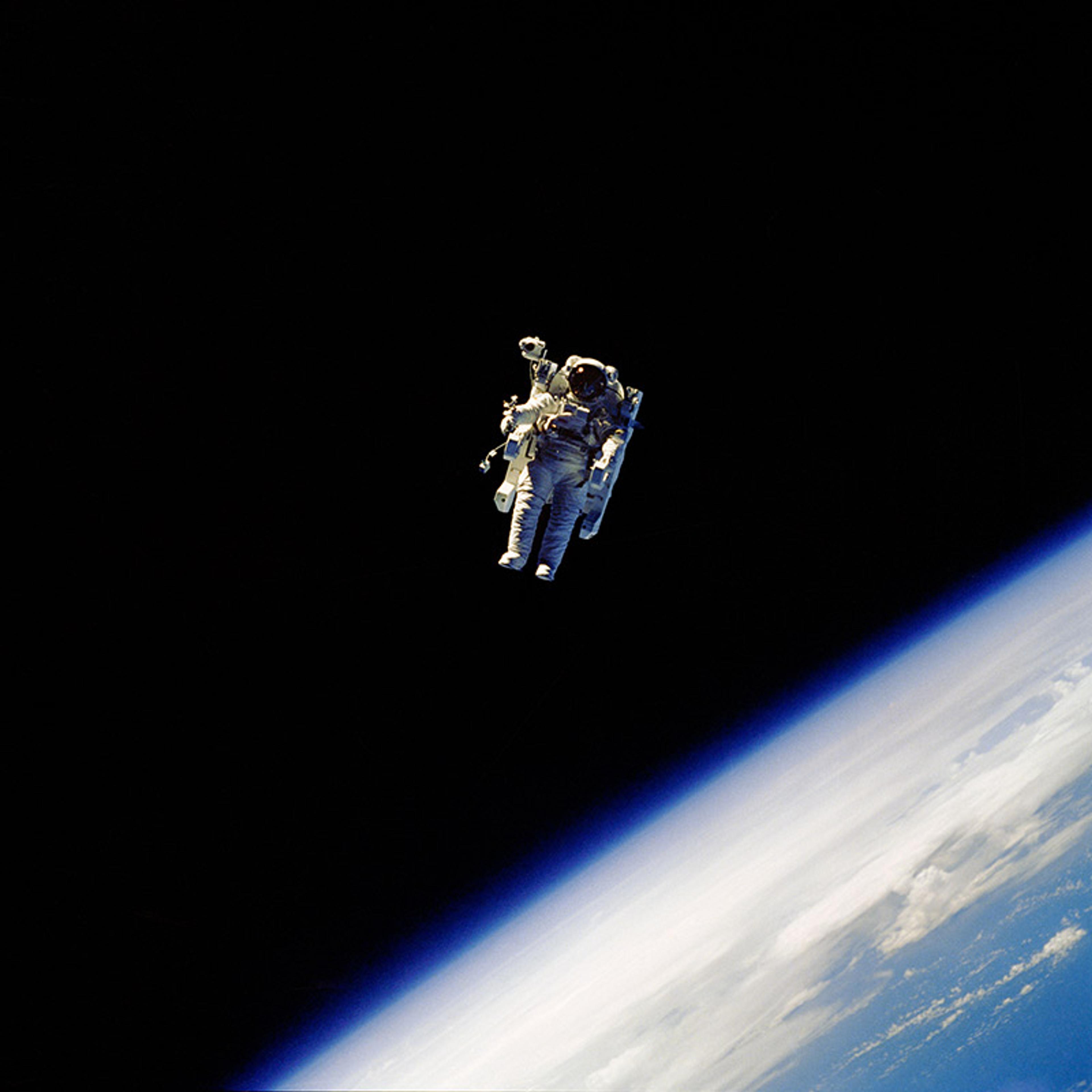 An astronaut in a spacesuit floating in outer space above Earth with a black background and Earth partially visible.