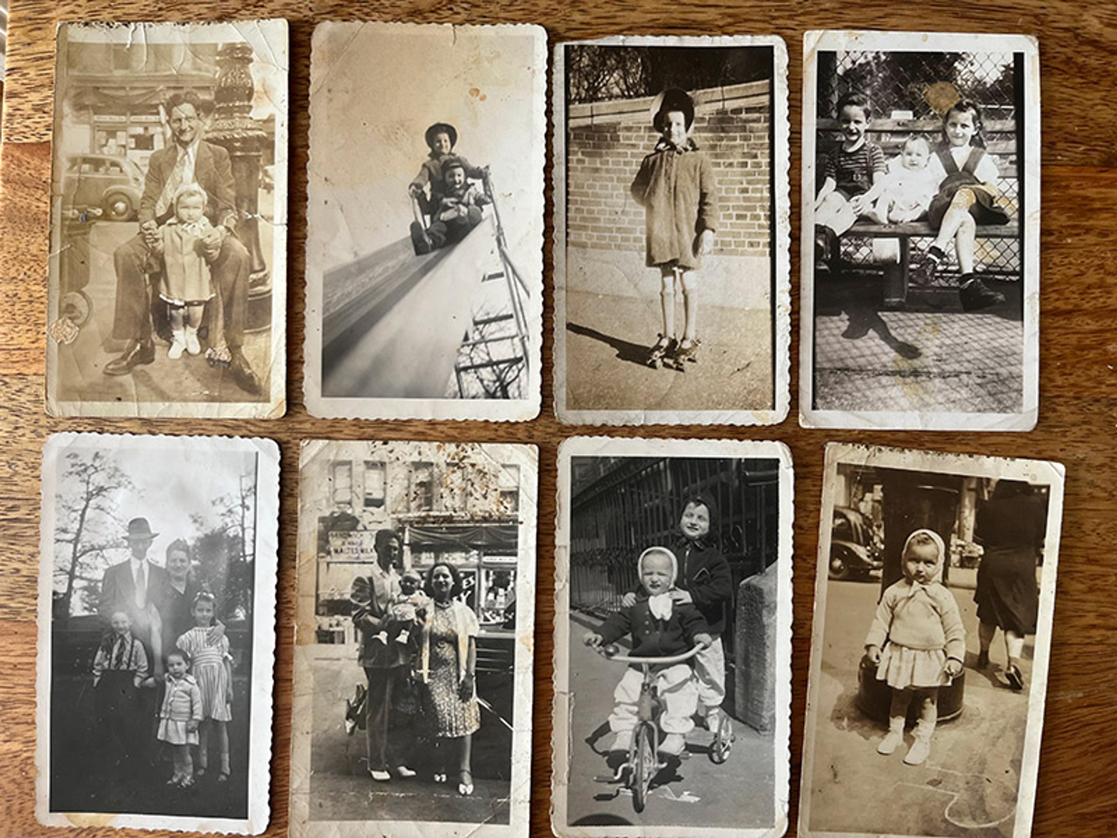 A collection of old black-and-white family photographs showing various vintage scenes with children and adults on a wooden table.