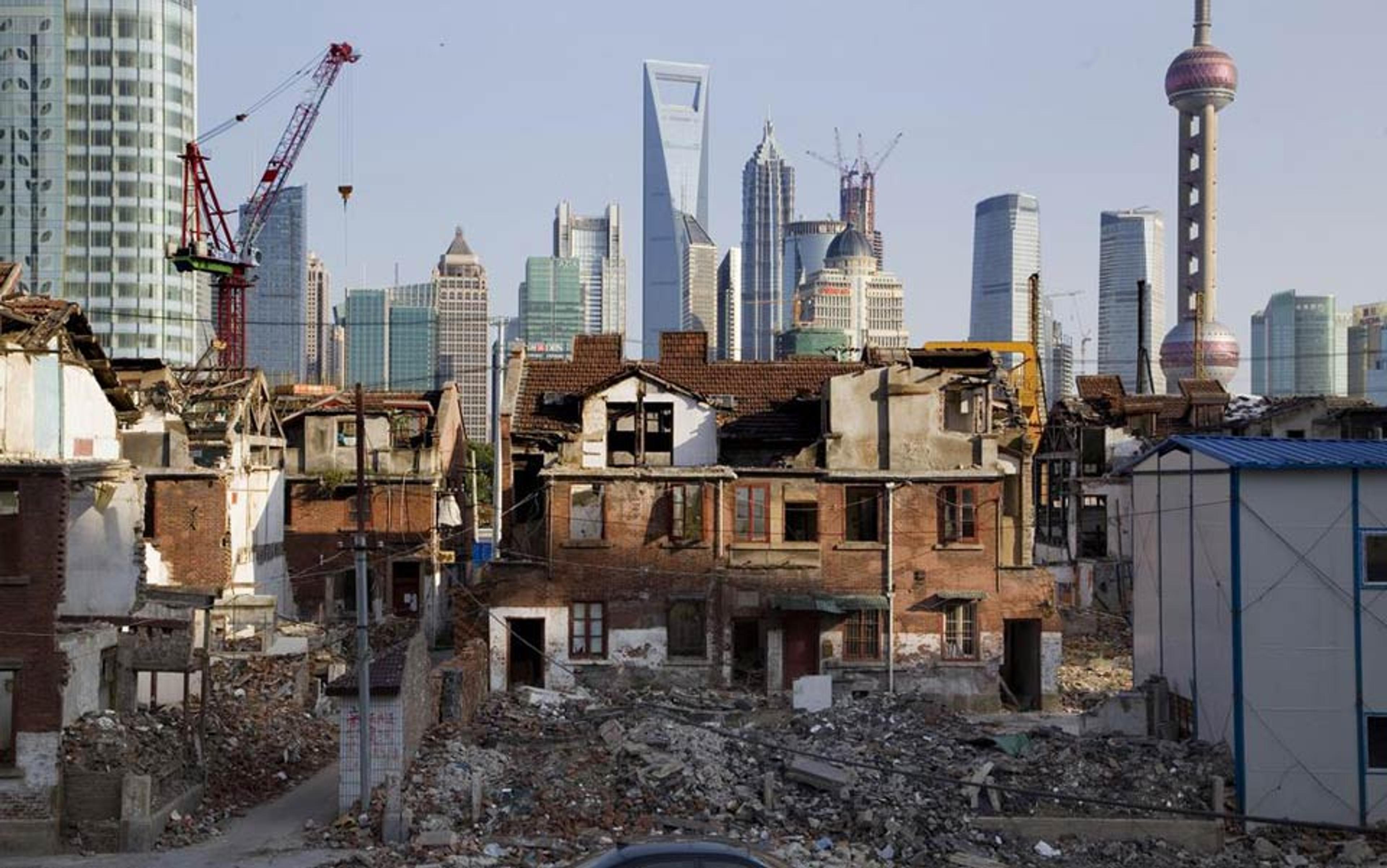 A cityscape featuring modern skyscrapers in the background with dilapidated, partially demolished buildings in the foreground.