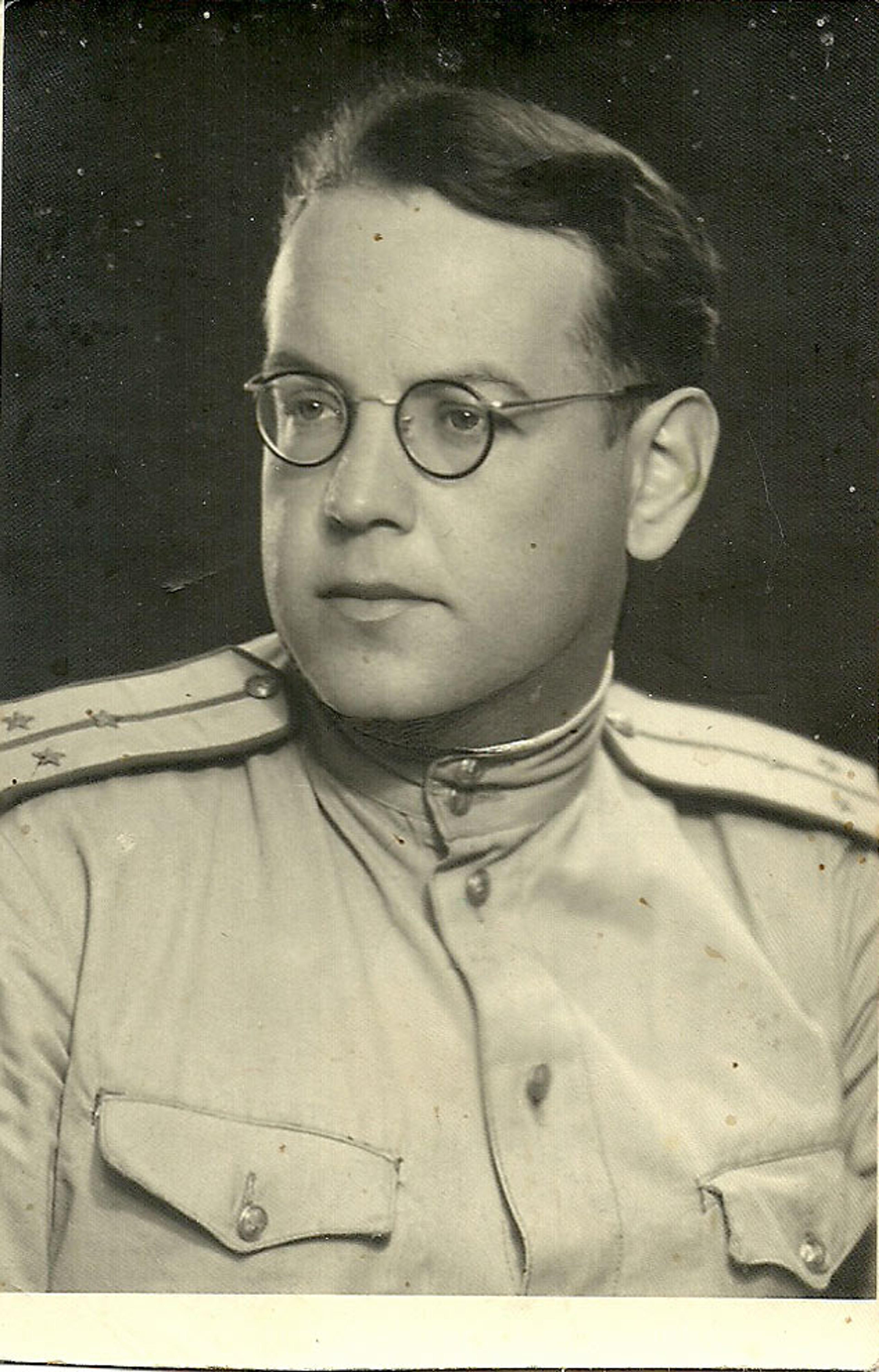 Black and white photo of a white man in a military uniform with star insignia and round glasses, facing slightly to the left.