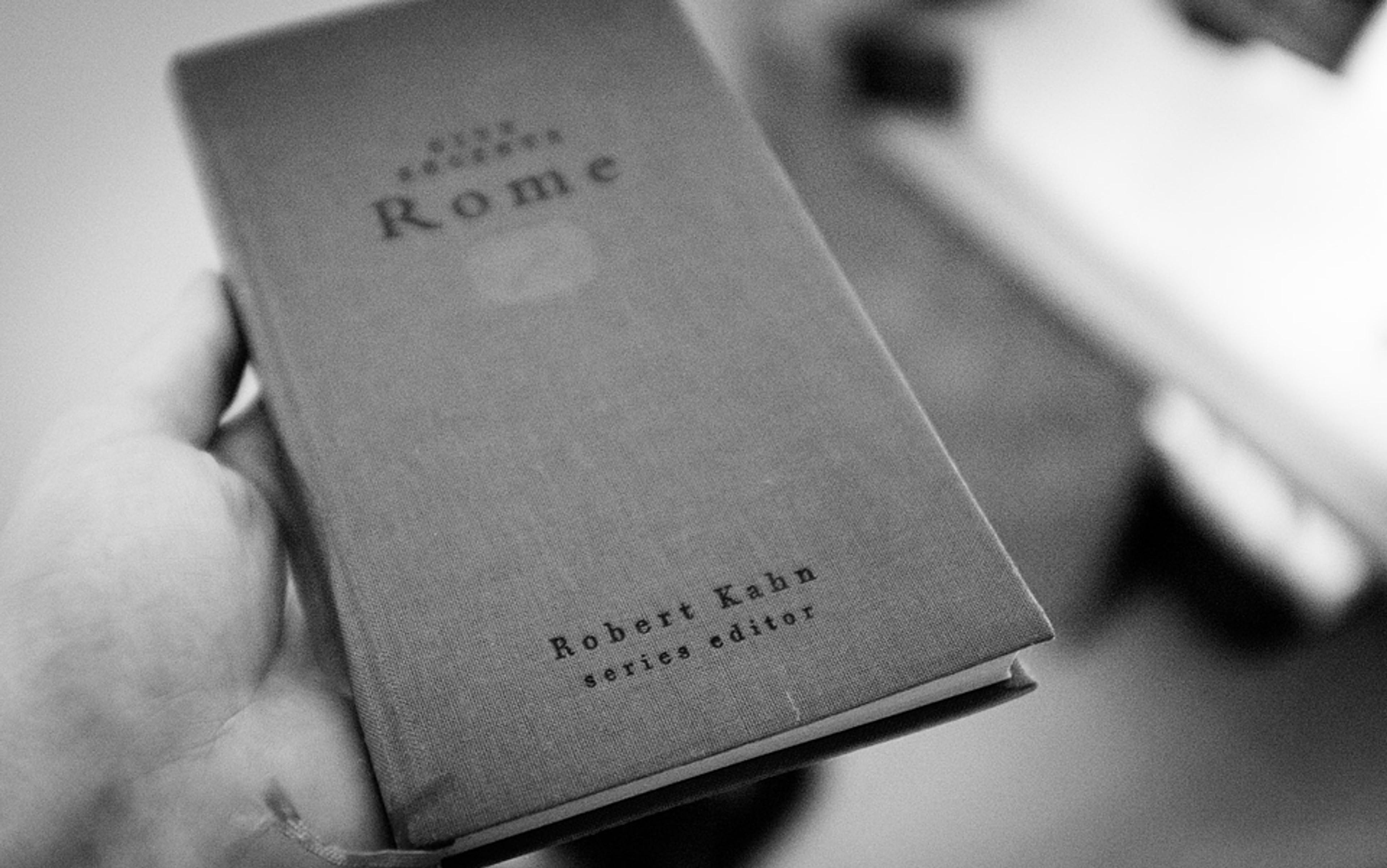 Black and white photo of a hand holding a book titled “Rome” with Robert Kahn as the series editor.