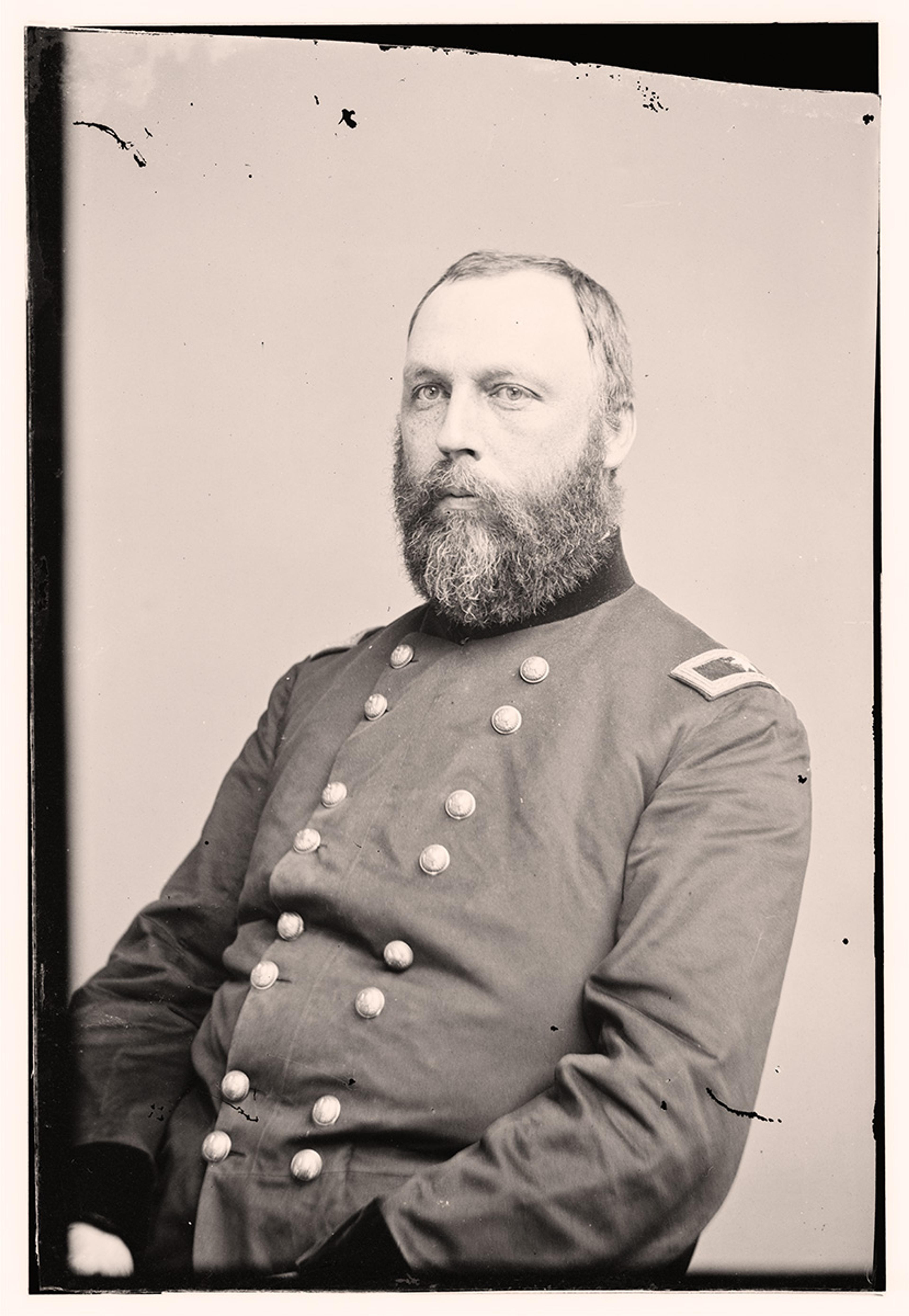 Vintage photo of a bearded man in a military uniform, seated.